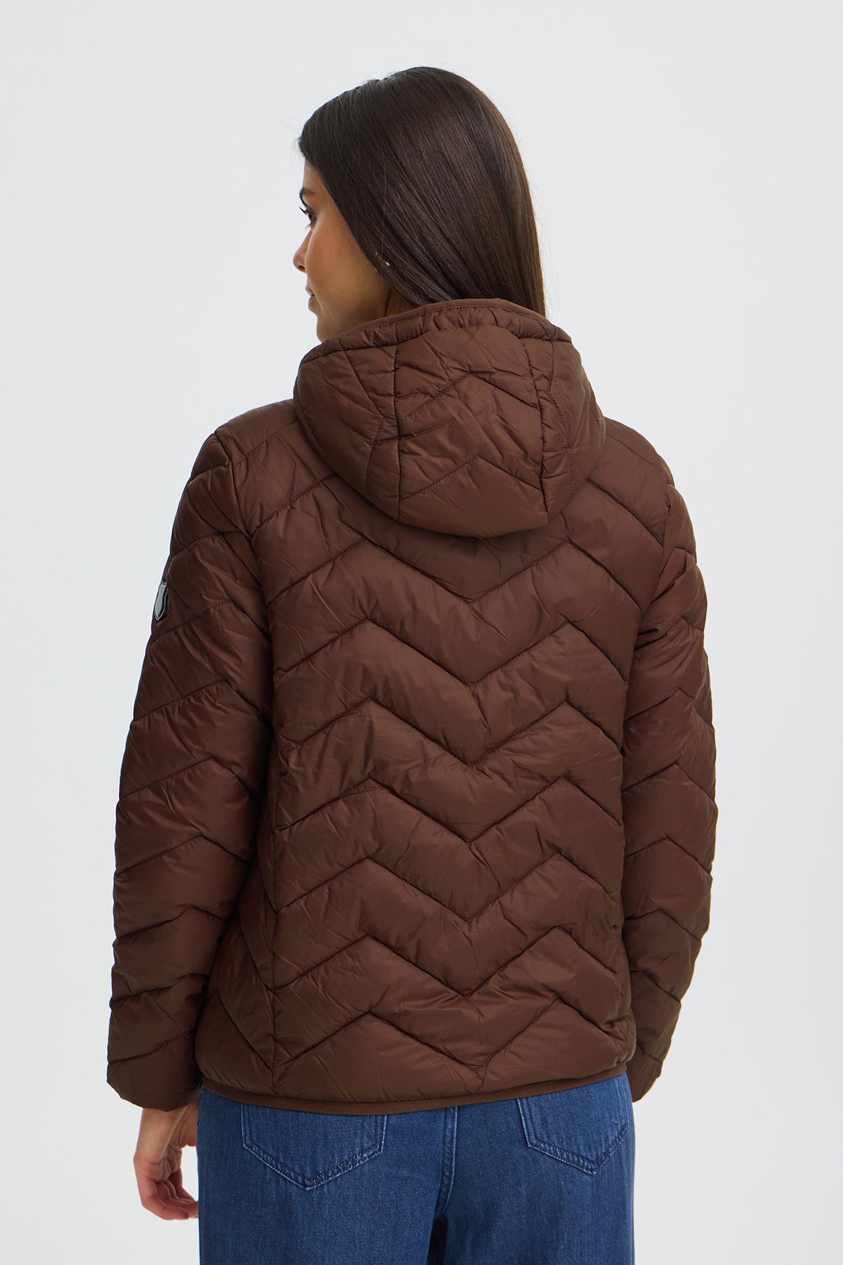 Mørkebrun pufferjakke med hætte og v-formede quiltinger set bagfra.