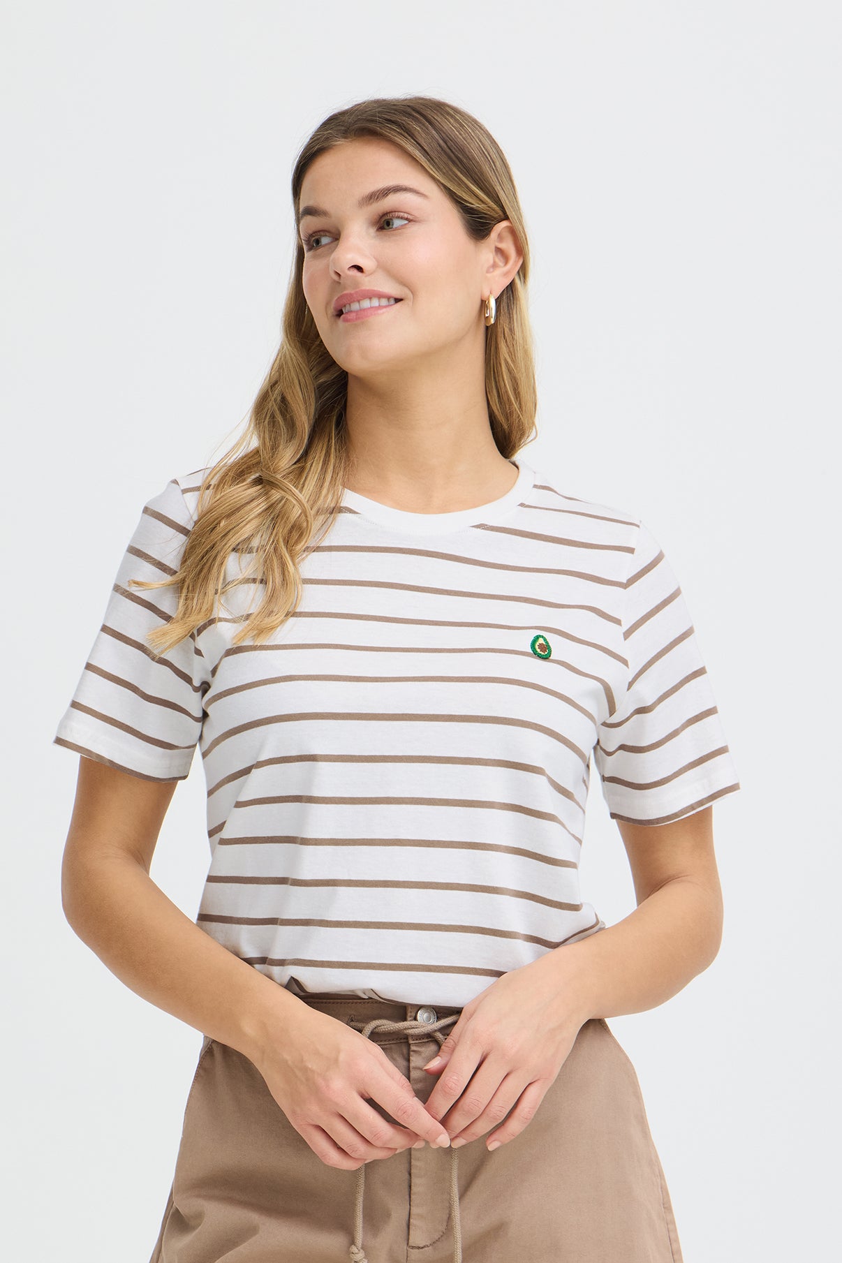 Hvid t-shirt med tynde brune striber og lille grøn broderet detalje på brystet.