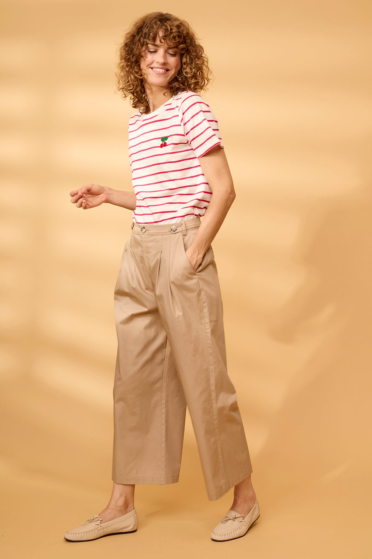 Hvid og rødstribet kortærmet t-shirt med broderet detalje og beige løstsiddende bukser.