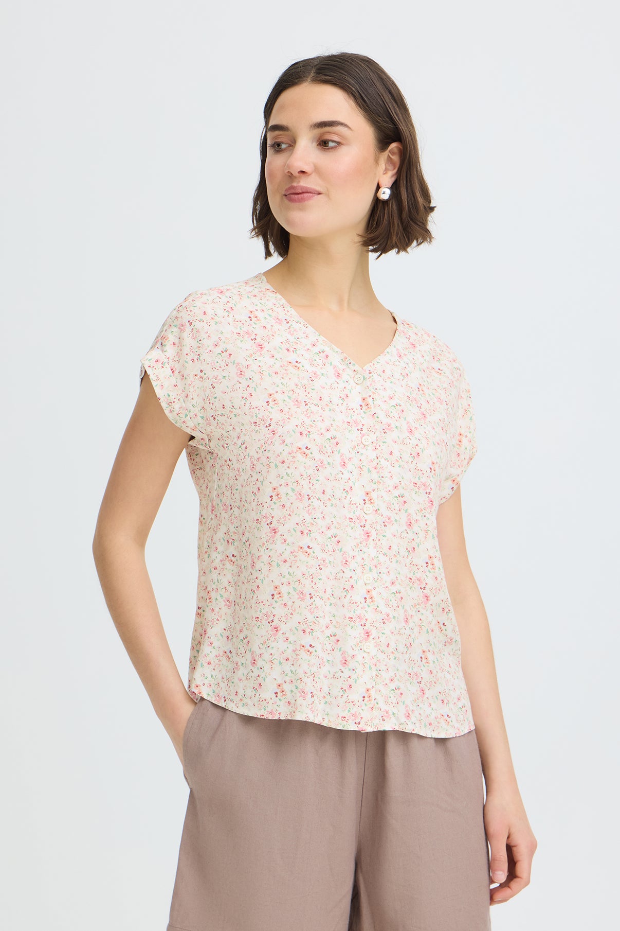 Kortærmet skjortebluse med lyserødt blomsterprint på hvid bund og V-hals.