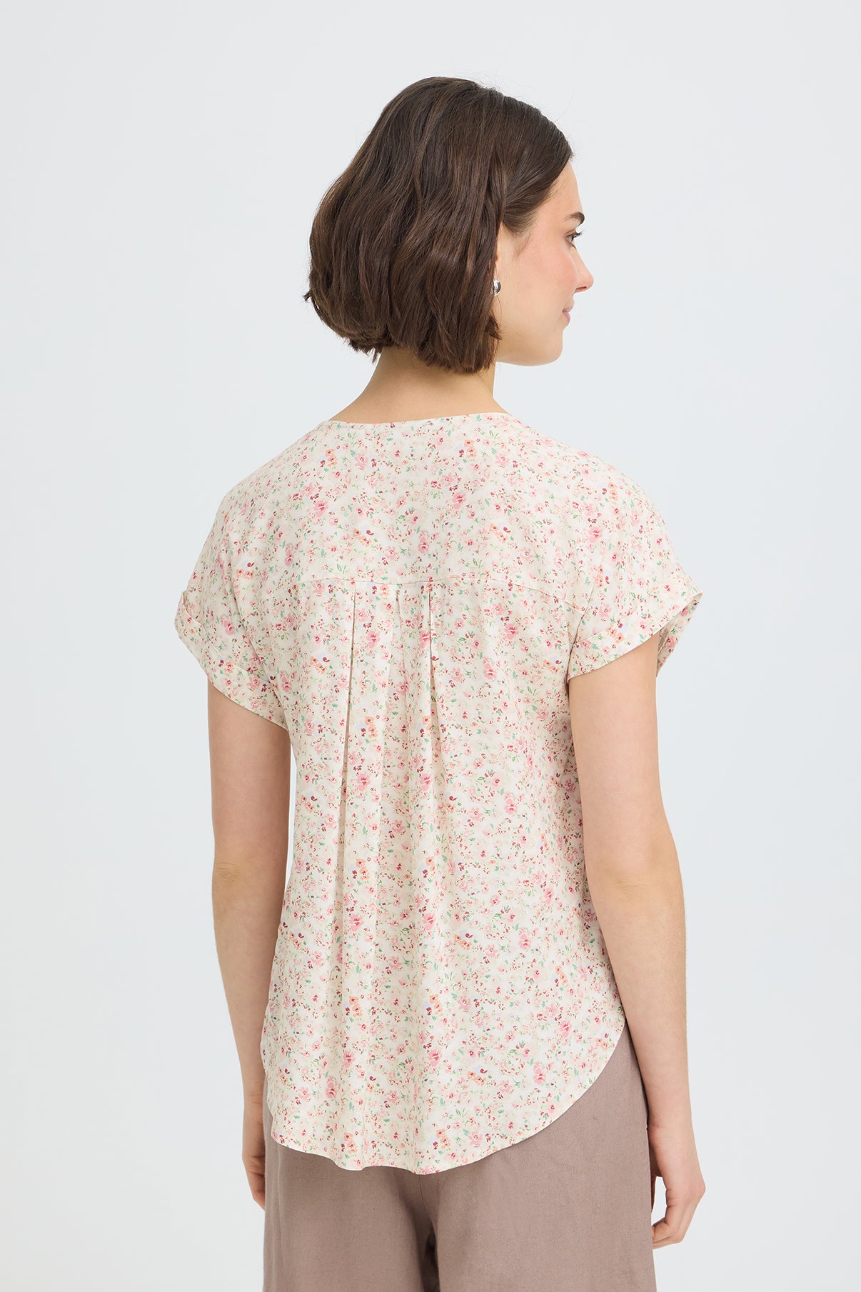 Kortærmet skjortebluse med blødt lyserødt blomsterprint og rundet kant bagpå.
