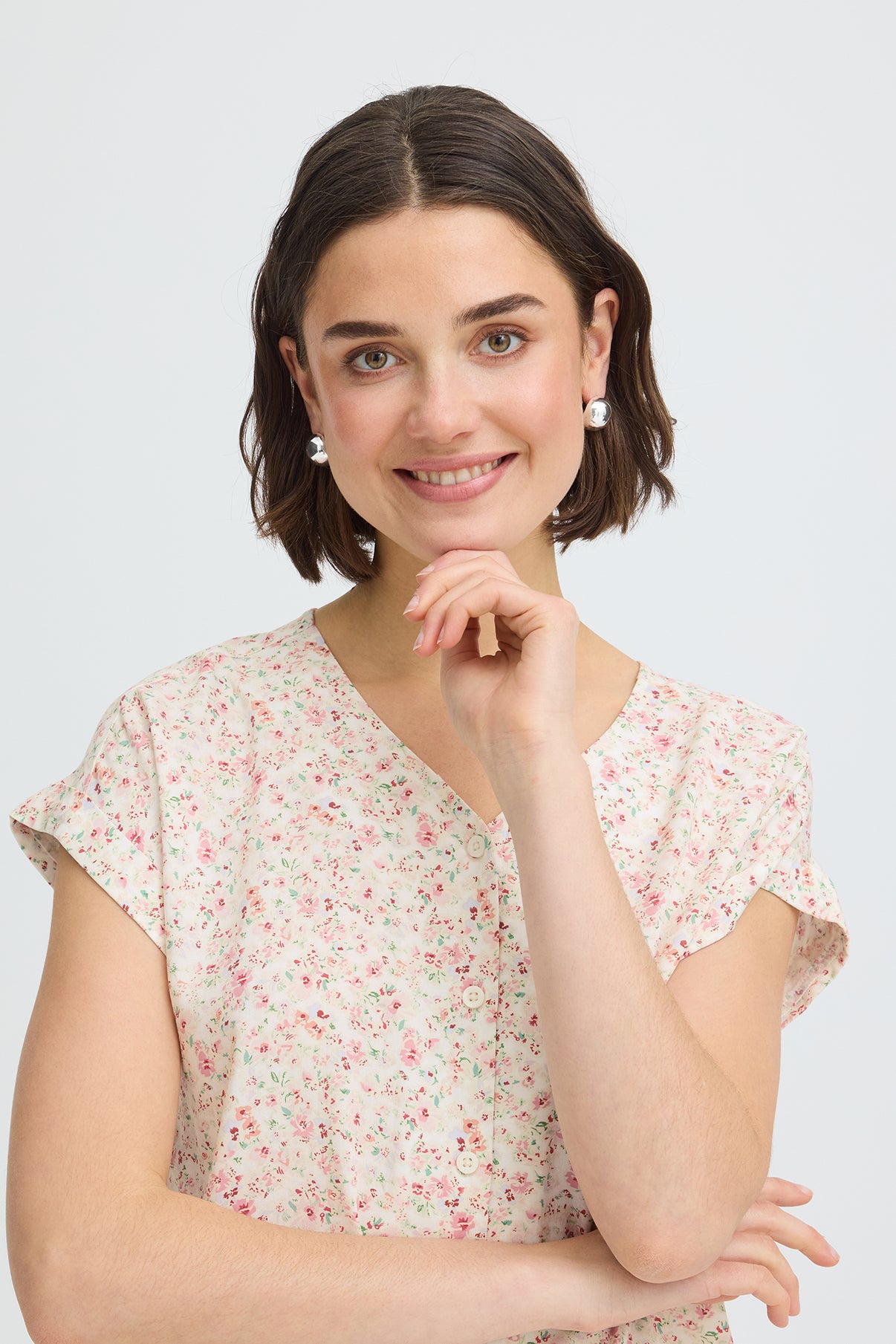 Kortærmet skjortebluse med blødt rosa og koralfarvet blomsterprint og V-hals.