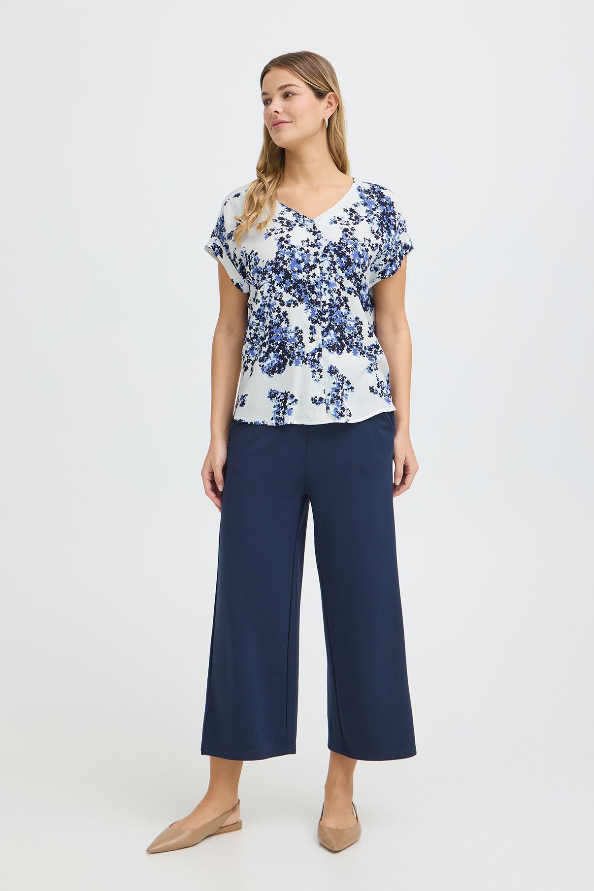 Kortærmet hvid skjortebluse med blå blomstret print og V-hals.