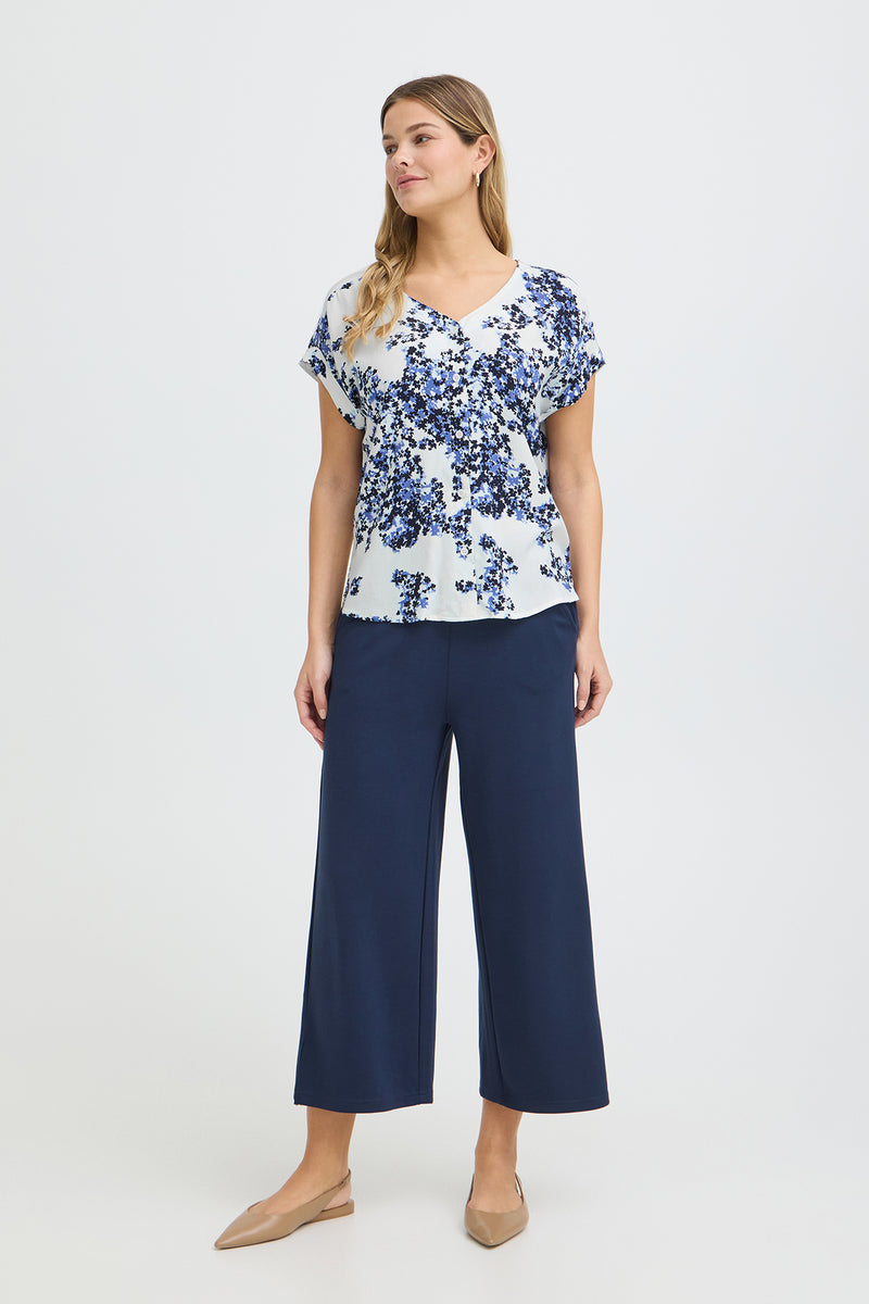 Kortærmet hvid skjortebluse med blå blomstret print og V-hals.