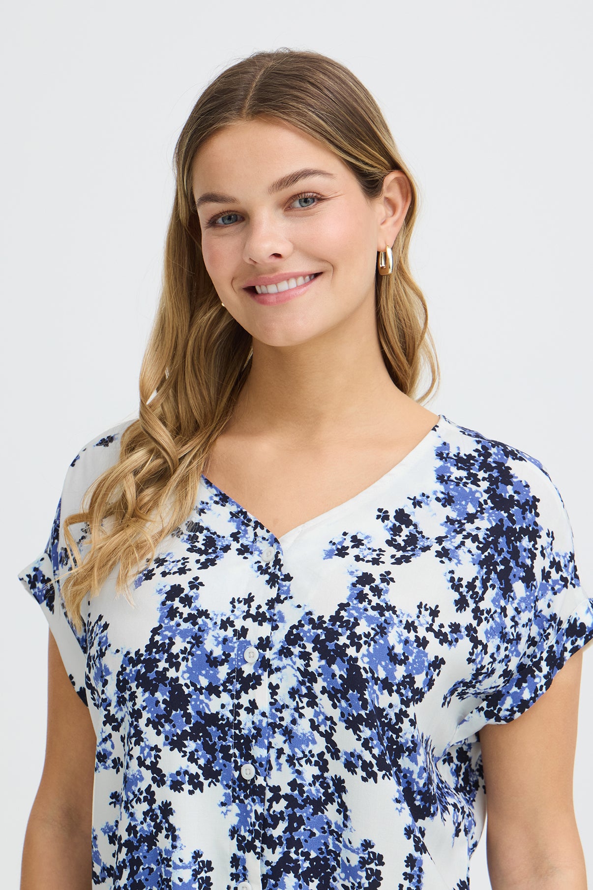 Kortærmet skjortebluse i hvid med blå blomsterprint og V-hals.