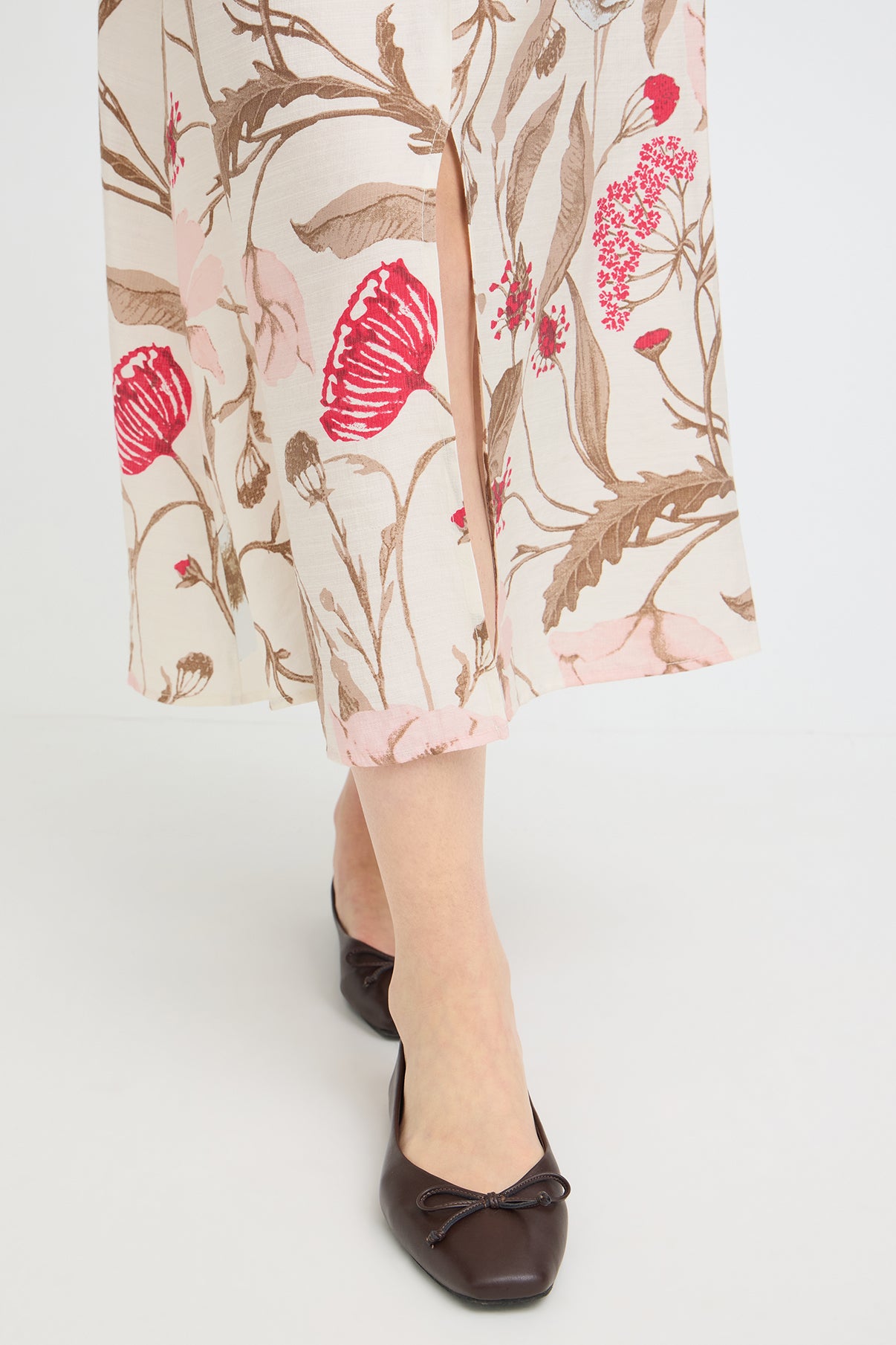 Lang beige nederdel med røde og brune blomsterprint og slids, set fra neden.