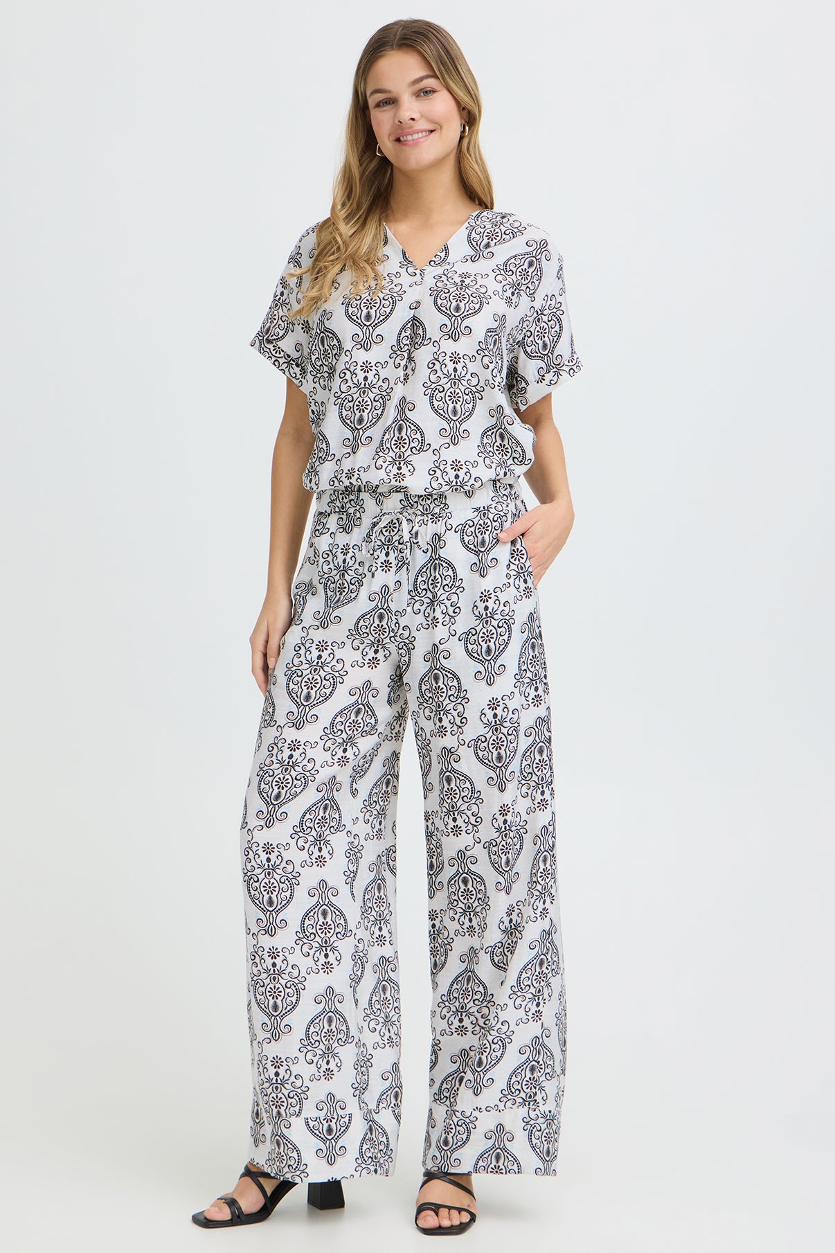 Løse hvide bukser med sort boho-mønster og løs pasform, kombineret med matchende top.