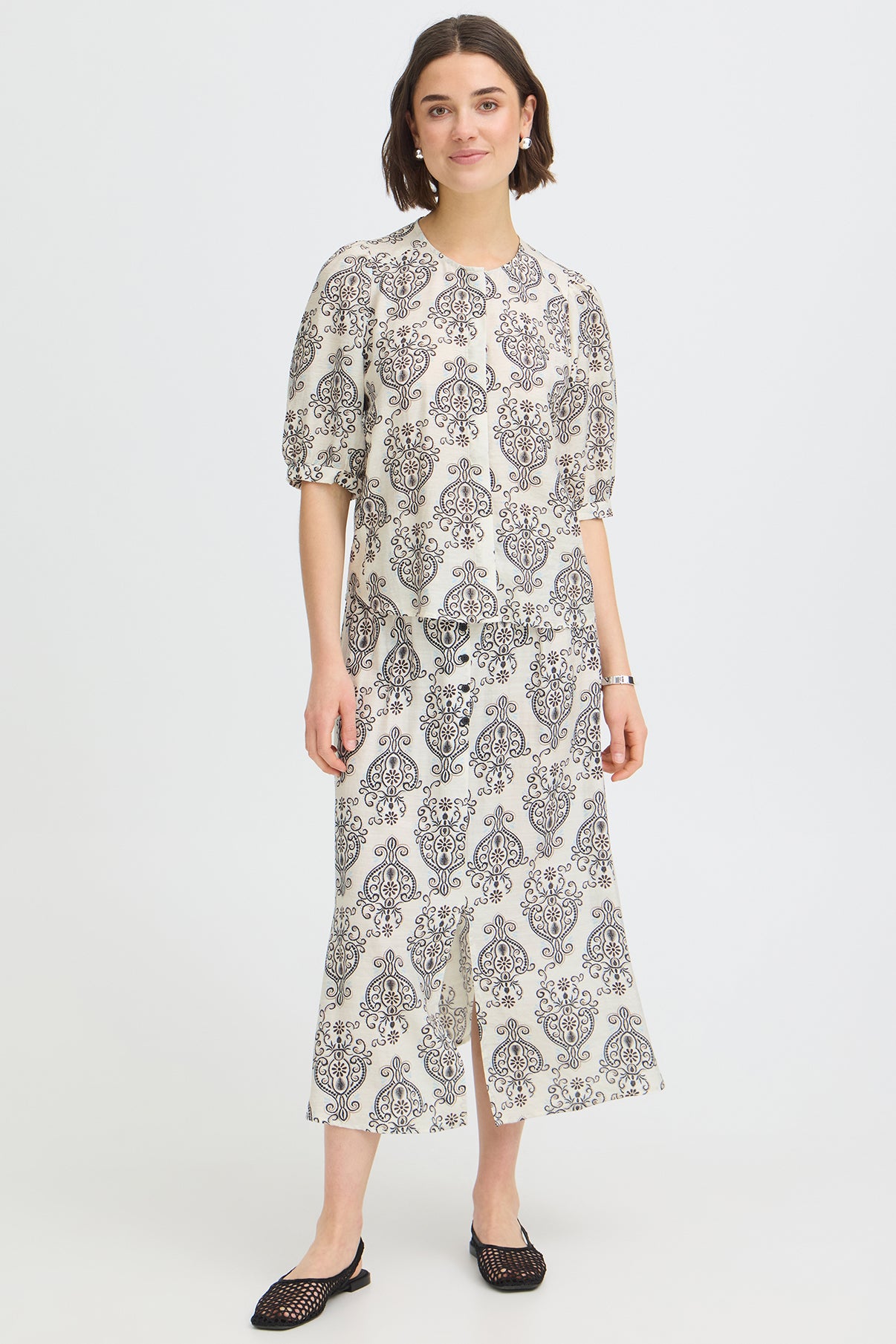 Kortærmet bluse med rund hals og sort-hvidt boho-mønster på hvid bund.