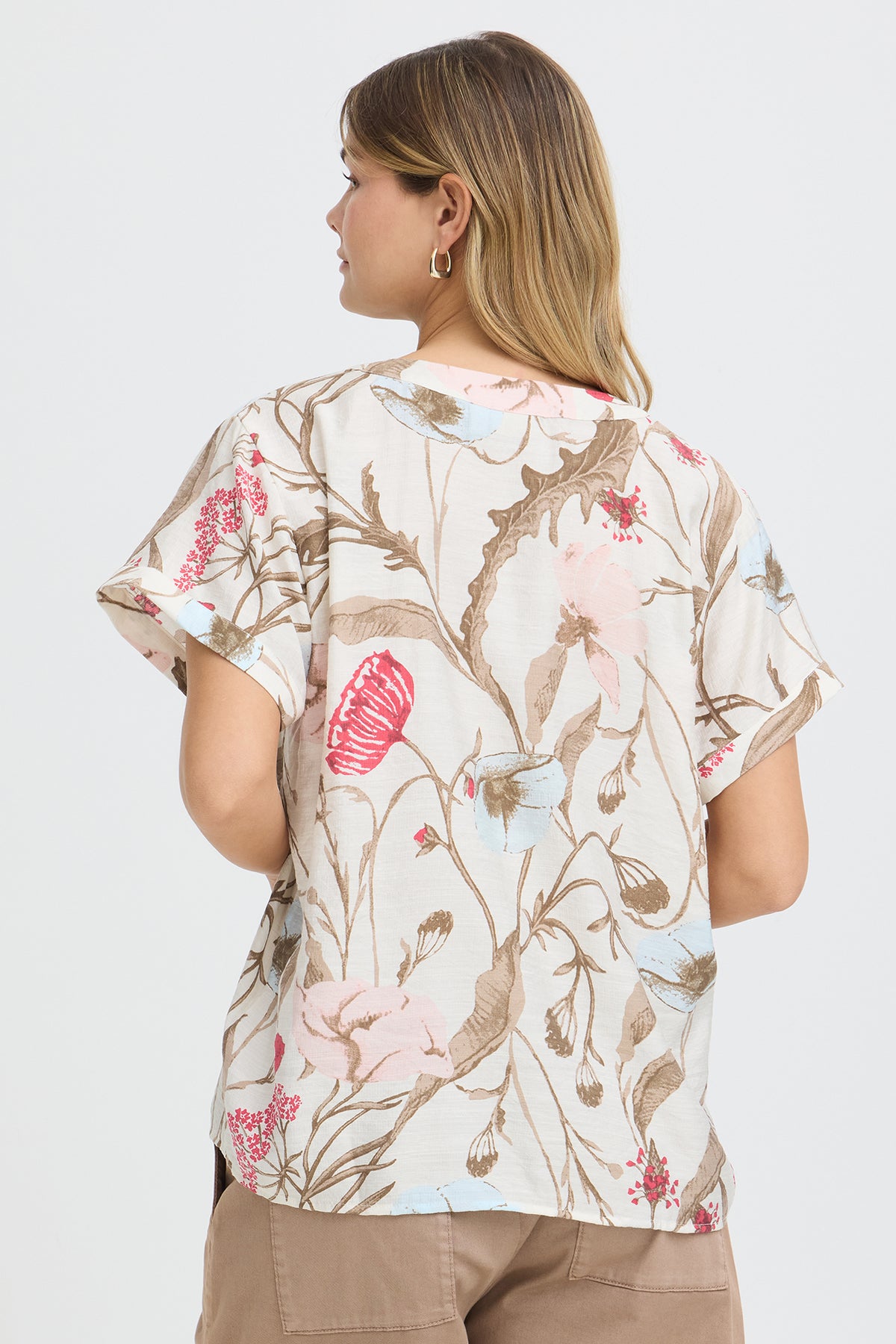 Kortærmet bluse med v-udskæring i blomstermønster, beige baggrund og rosa samt blå blomster.