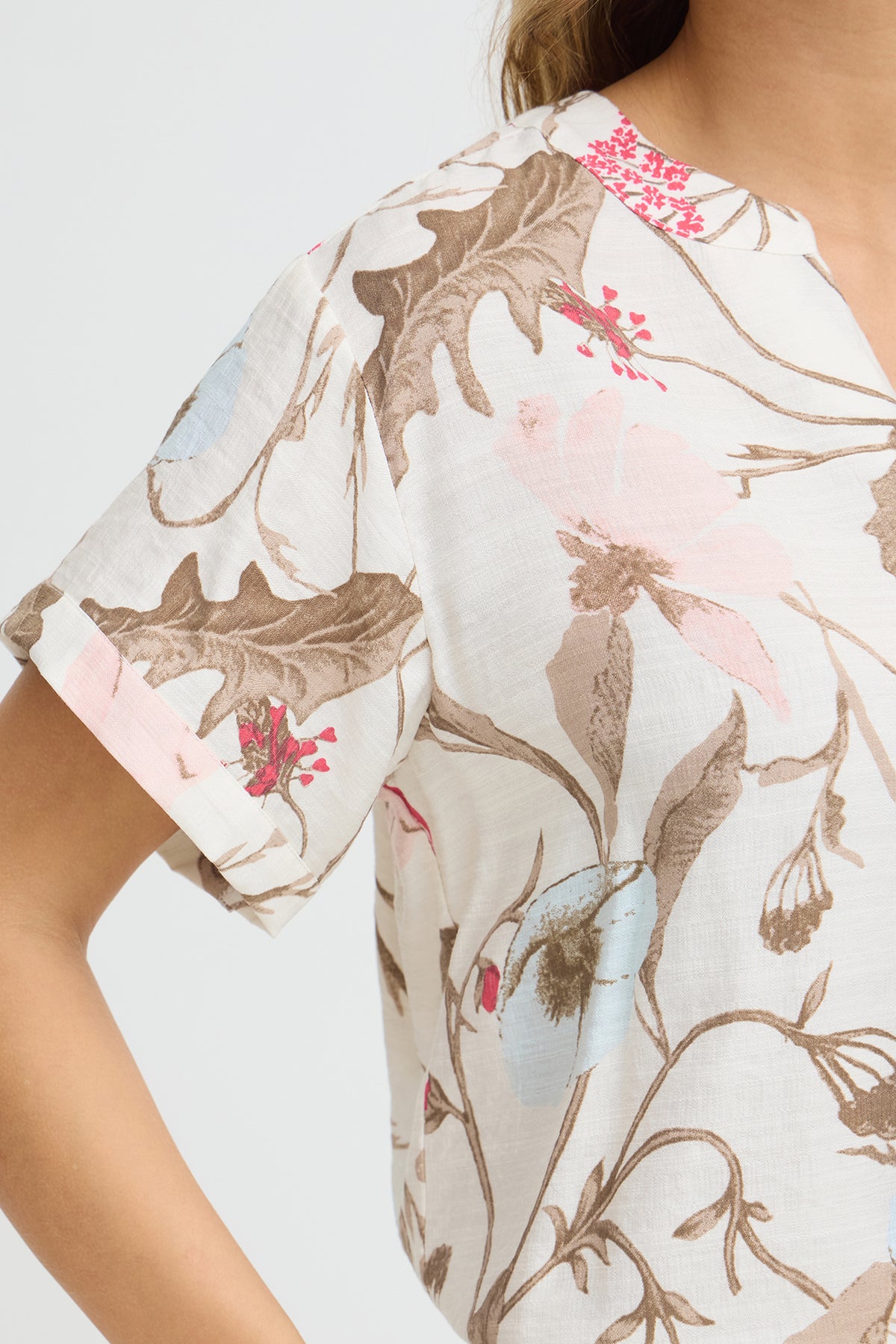 Kortærmet hvid bluse med v-udskæring og beige, lyseblå og pink blomsterprint.