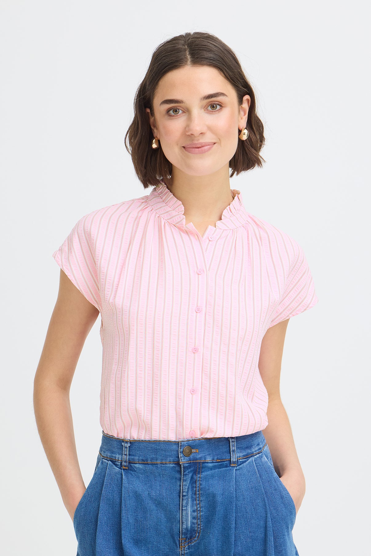 Kortærmet skjortebluse med pink, rød og hvide lodrette striber og flæsekant ved kraven.