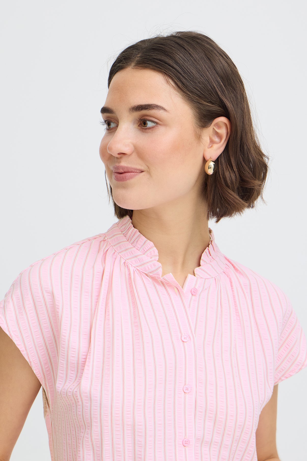 Kortærmet skjortebluse med pink, rød og hvide striber og let flæsekant ved kraven.