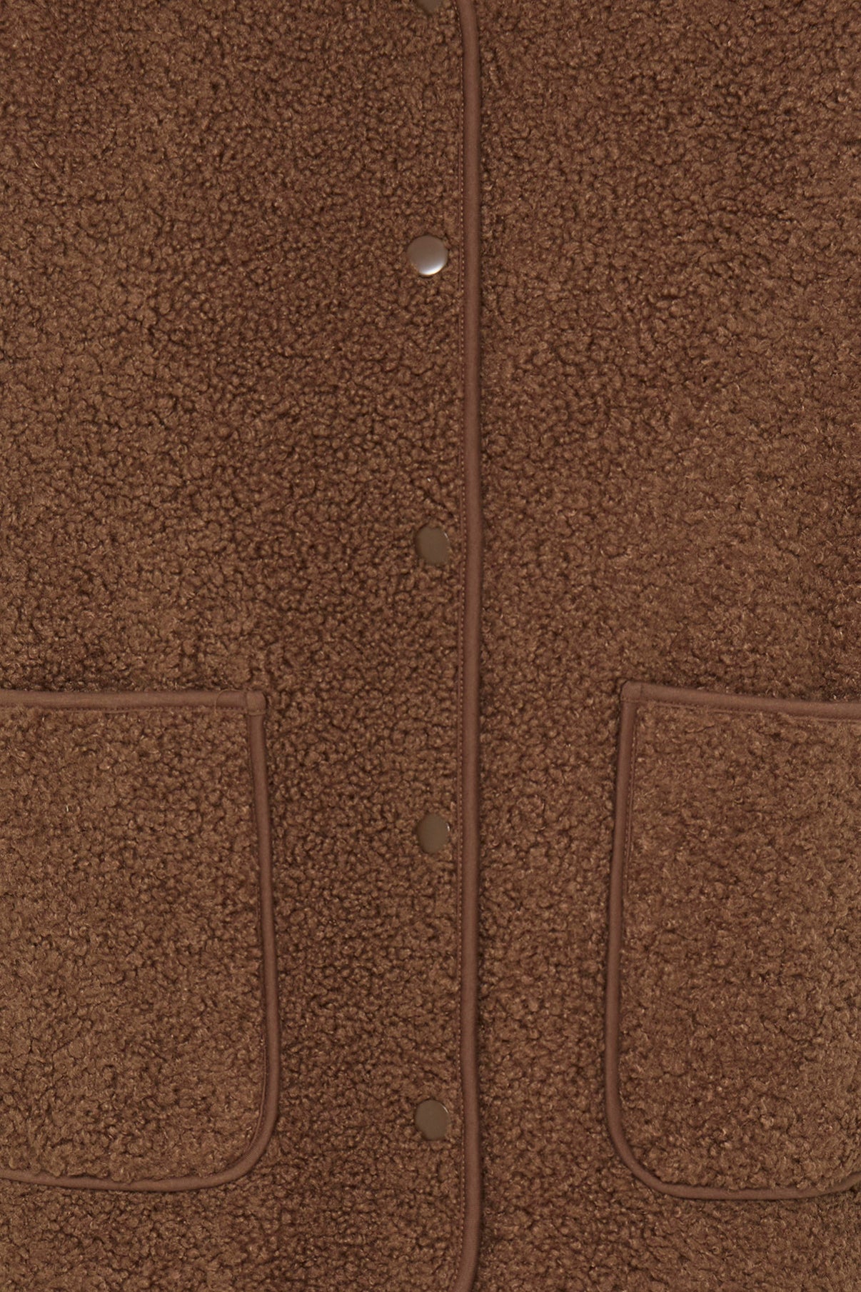 Brun teddy vest med knapper og to store forlommer i blødt, textured stof.