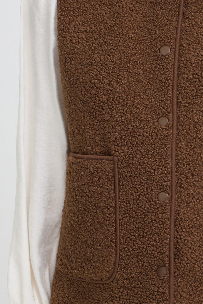 Brun teddy vest med knapper og stort forlomme, bæveragtig tekstur, casual design.