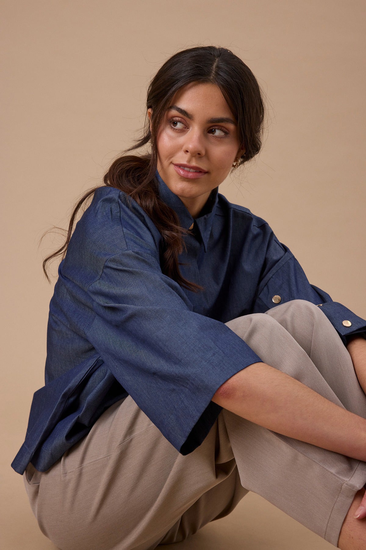 Mørkeblå skjortebluse i denimlook med trekvartærmer og klassisk krave, båret med lyse bukser.
