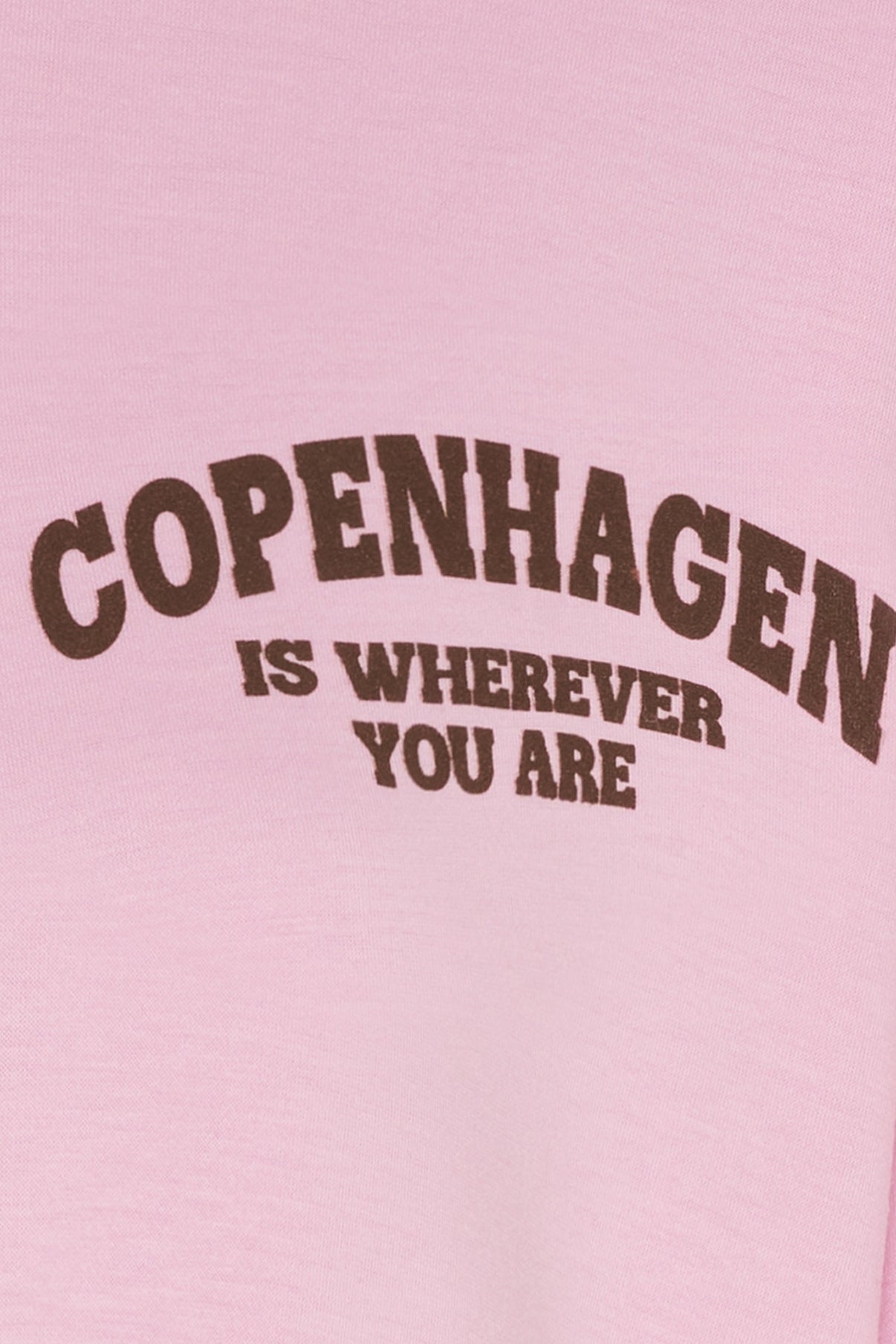 Lyserød t-shirt med brun tekst "Copenhagen Is Wherever You Are" på fronten.