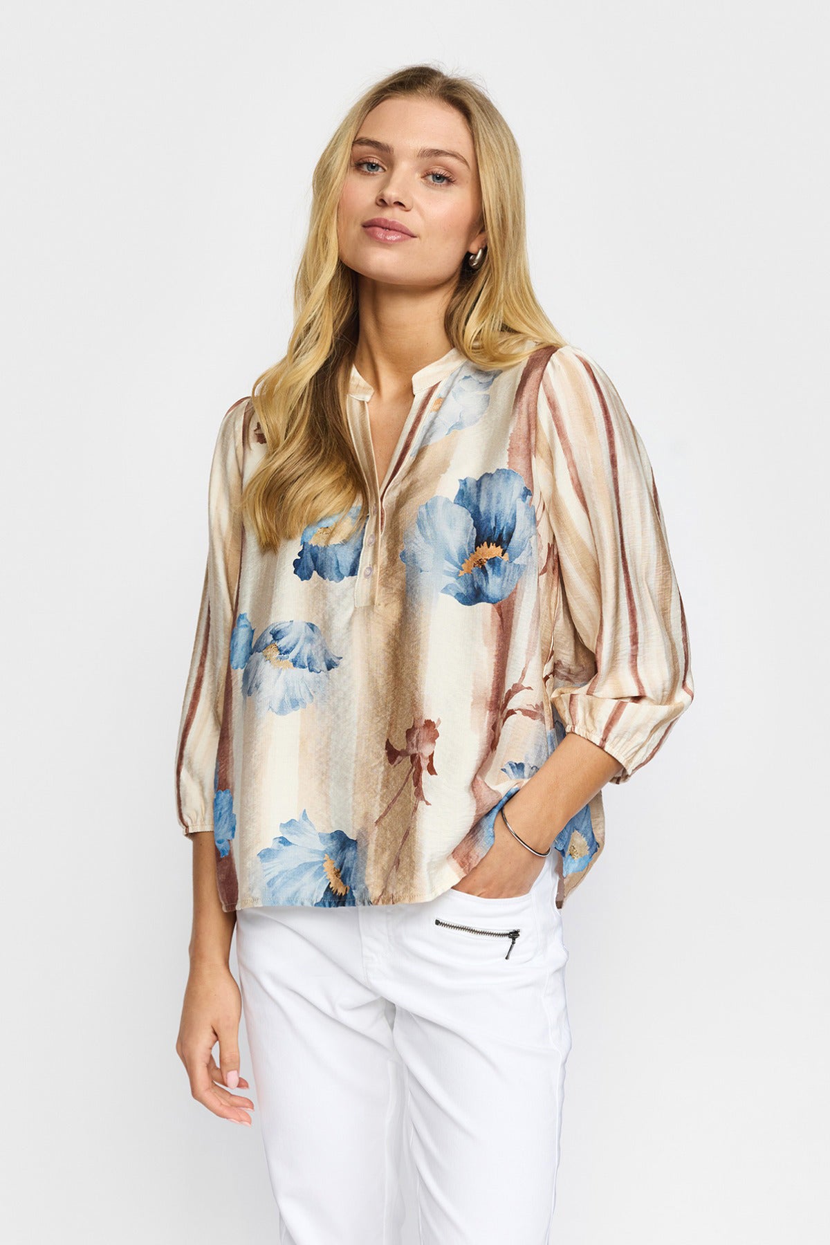 Sandfarvet bluse med blå blomster og trekvartærmer i let, flowy materiale.