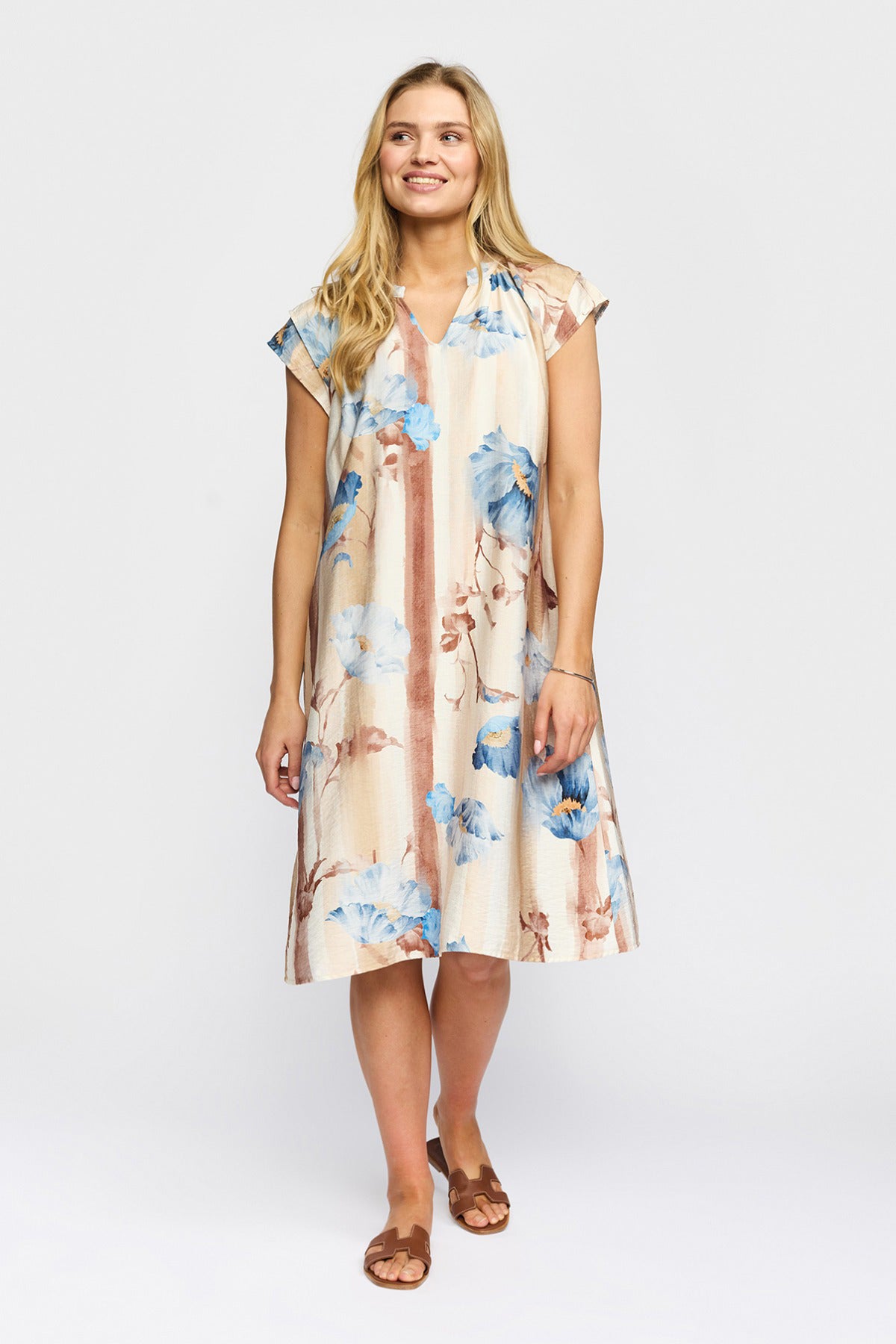 Kortærmet sandfarvet kjole med blomsterprint i blå og beige, midi-længde, løstsiddende cut.