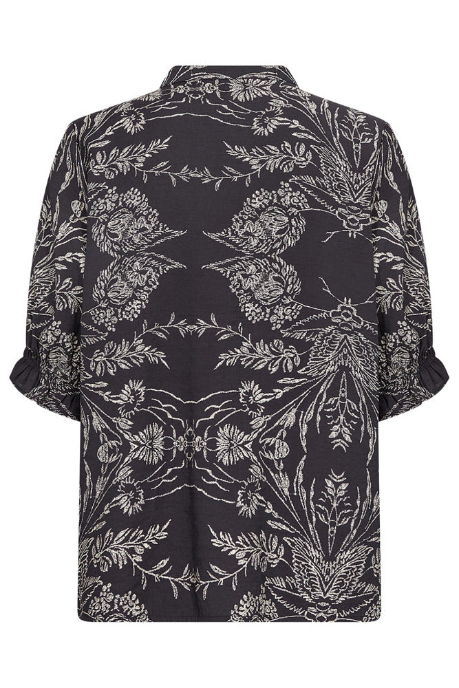 Kortærmet sort bluse med hvidt, symmetrisk blomster- og bladmønster.
