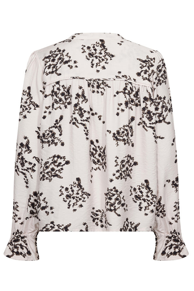 Langærmet hvid bluse med sort blomsterprint og let rynkede ærmekanter.