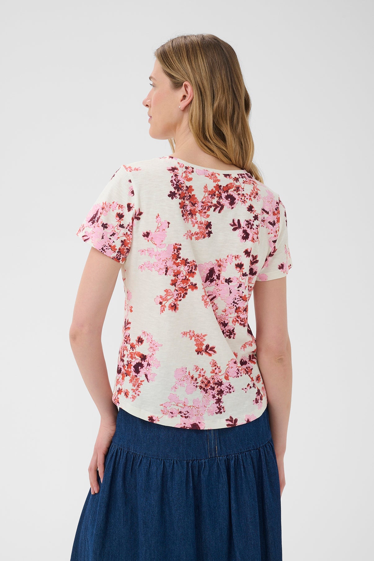 Kortærmet bluse med lyserødt og rødt blomsterprint på hvid baggrund, rund hals og løs pasform set bagfra.