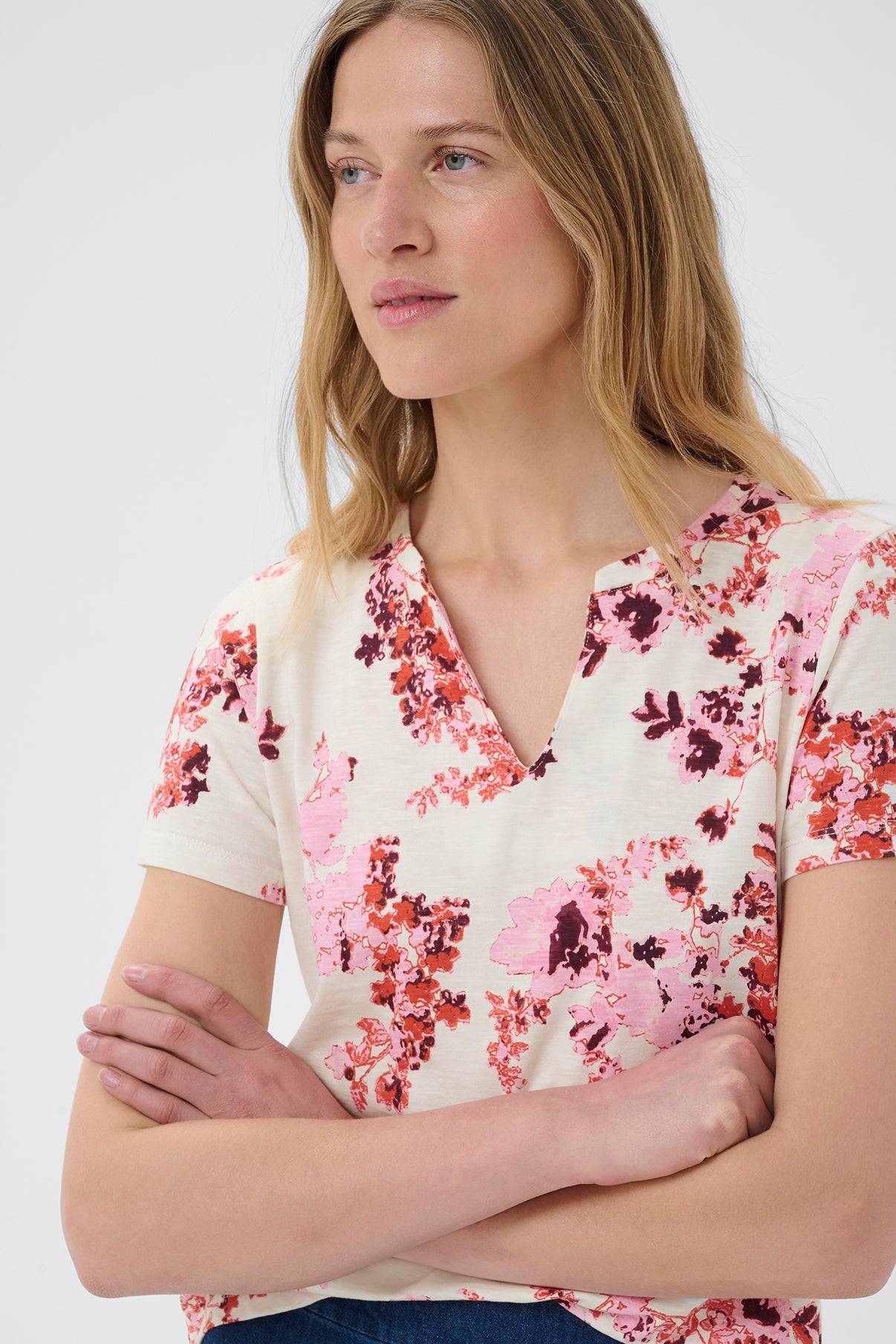 Kortærmet bluse med pink og rød blomstret print på lys cremegul baggrund.