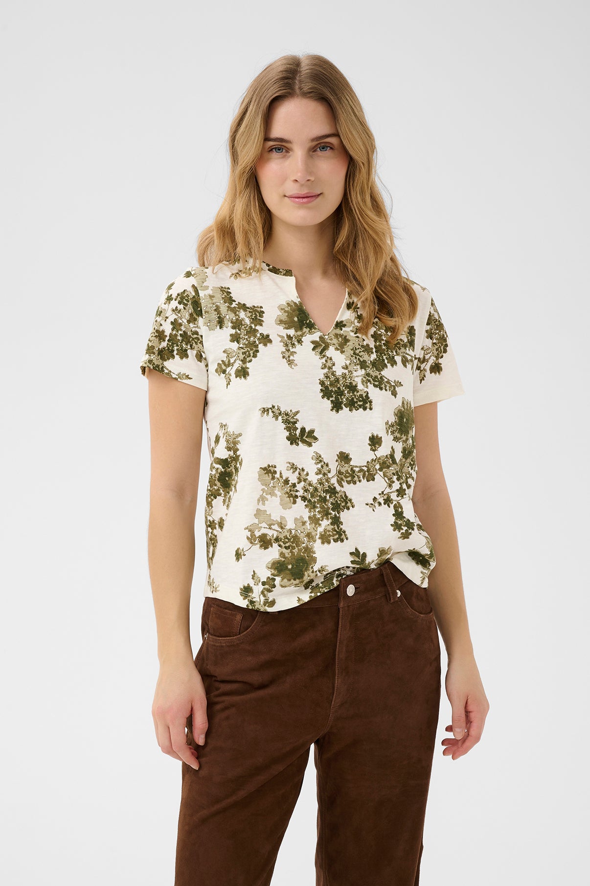 Kortærmet hvid bluse med grønne blomsterprint og rund hals.