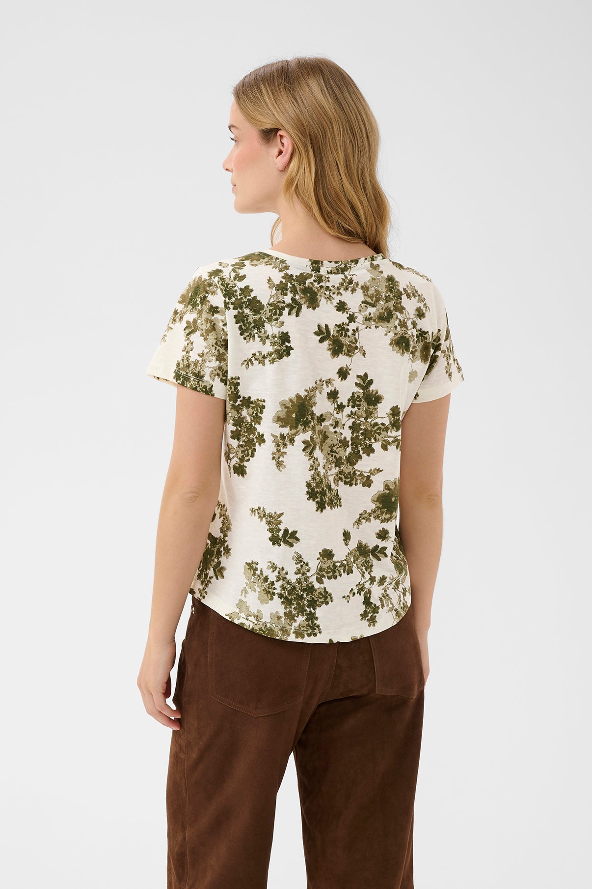 Kortærmet bluse med grønne blomster på hvid bund, rund hals og løs pasform set bagfra.