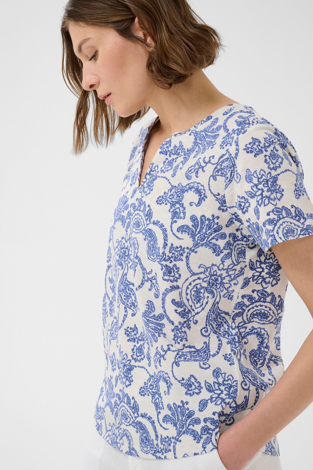 Kortærmet bluse med blå paisleyprint på hvid baggrund og rund halsudskæring.