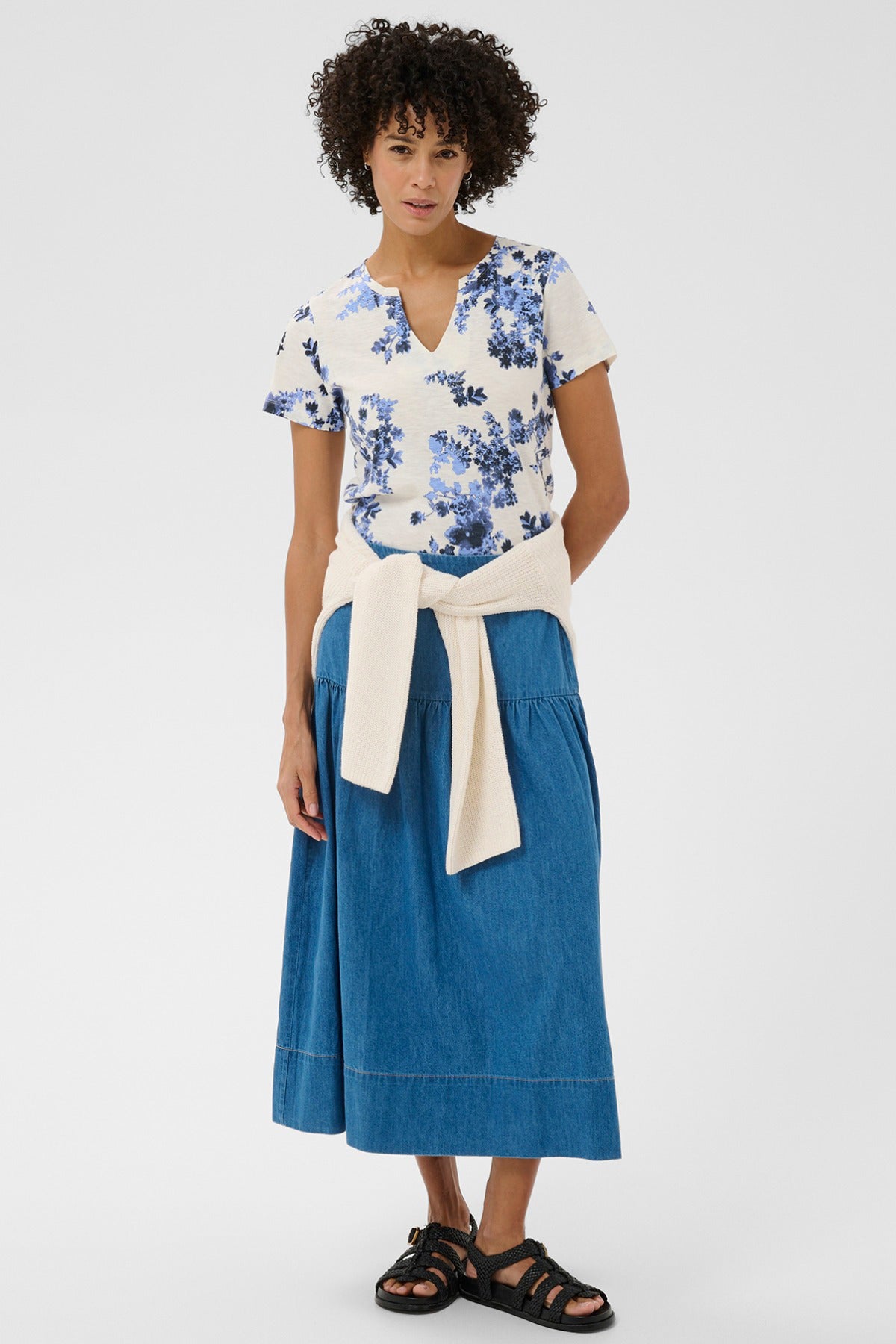 Kortærmet hvid bluse med blå blomsterprint og v-hals.