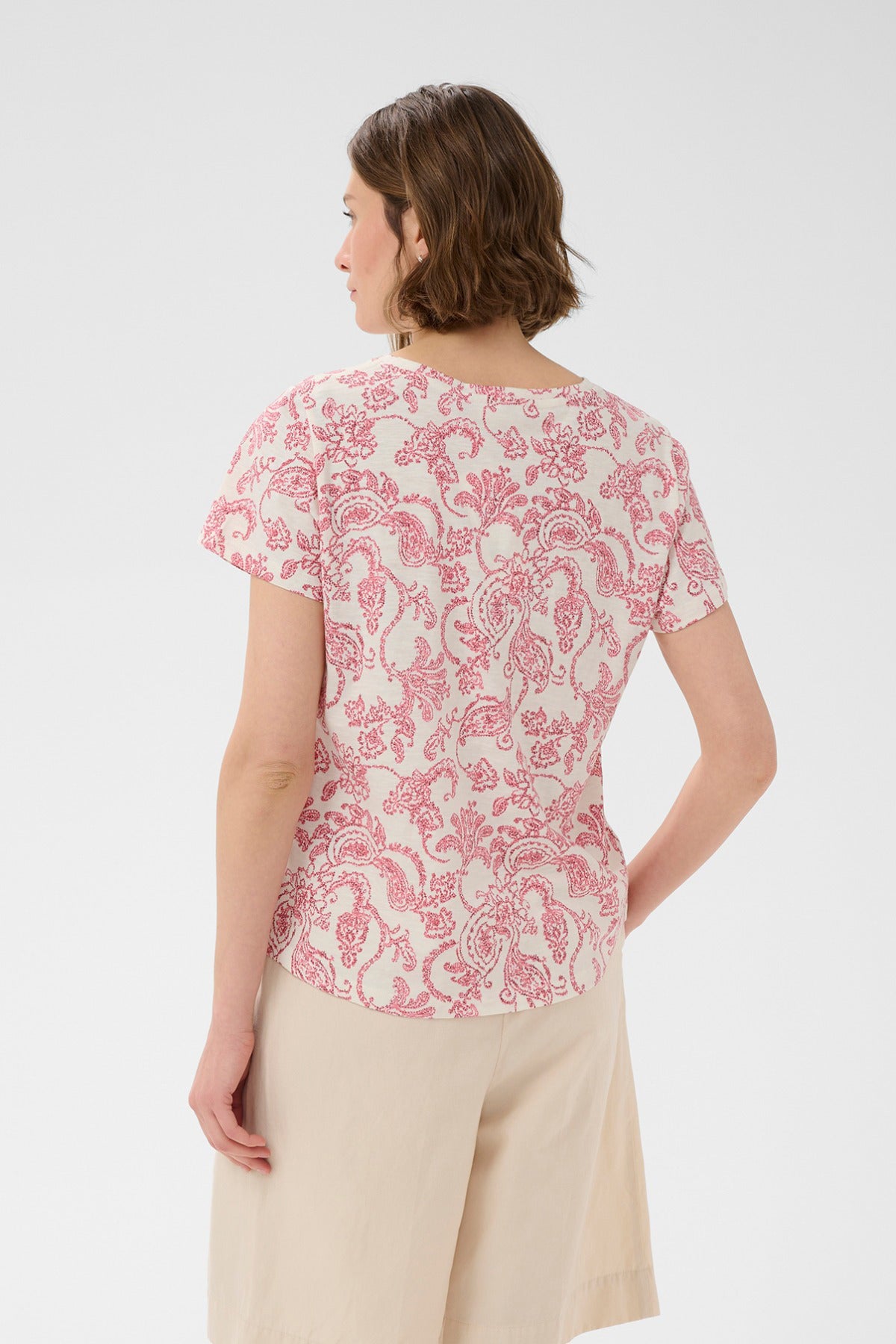 Kortærmet bluse med lyserød paisleyblomstret print og rund hals, set bagfra.