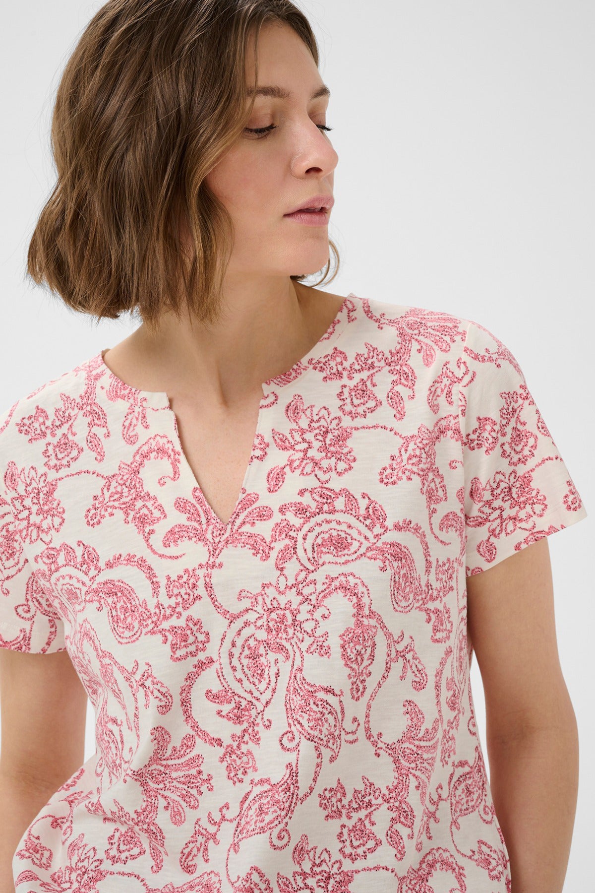 Kortærmet bluse med pink paisley- og blomsterprint på hvid bund, rund hals med slids.
