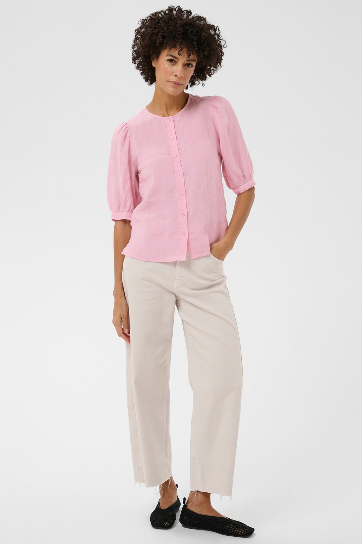 Rosa bluse med rund hals, korte ærmer og knaplukning foran, båret med beige bukser.