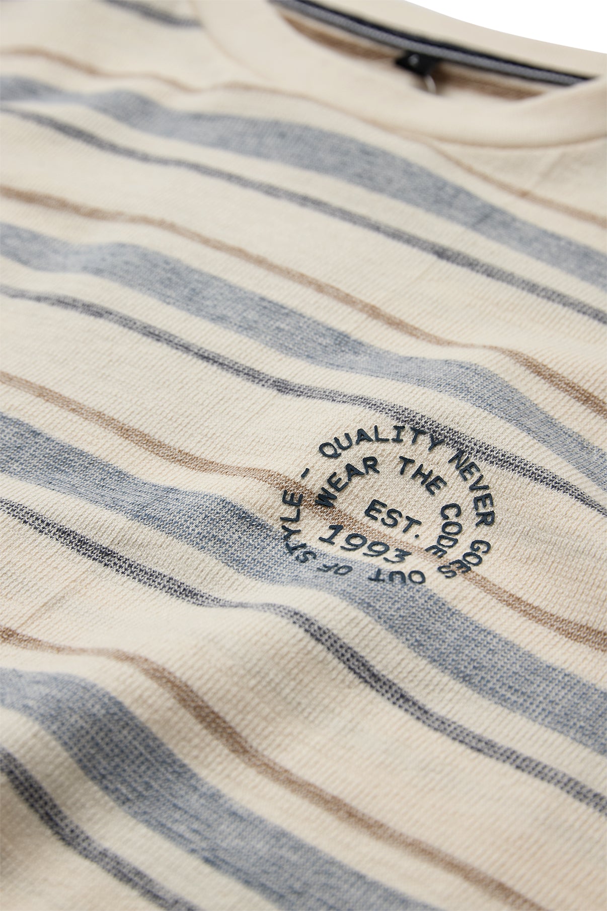 Blå og beige stribet t-shirt med rund sort trykt tekst og crewneck hals.