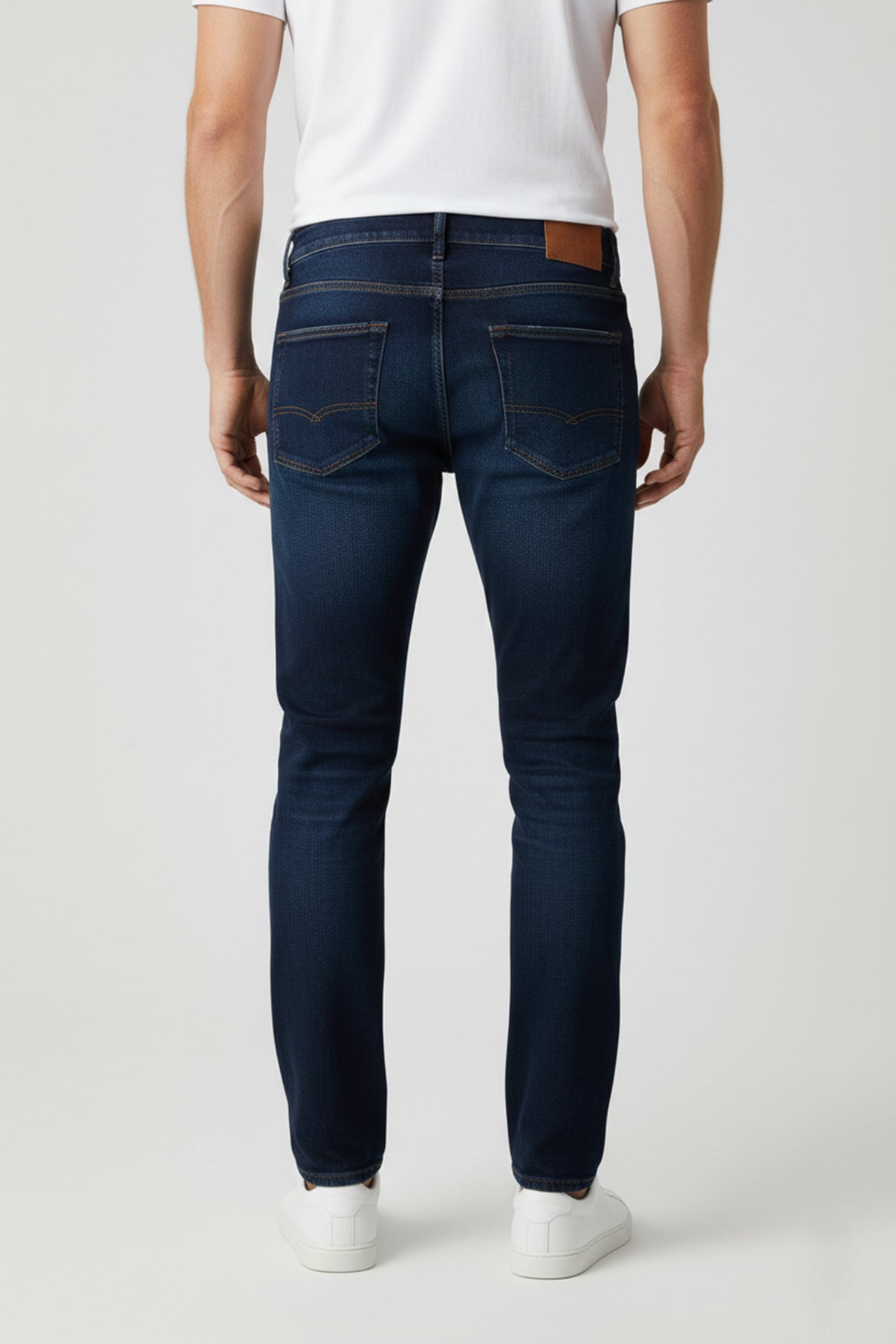 Mørkeblå stretchjeans med smal pasform og baglommer med syninger, slidte detaljer bagpå.