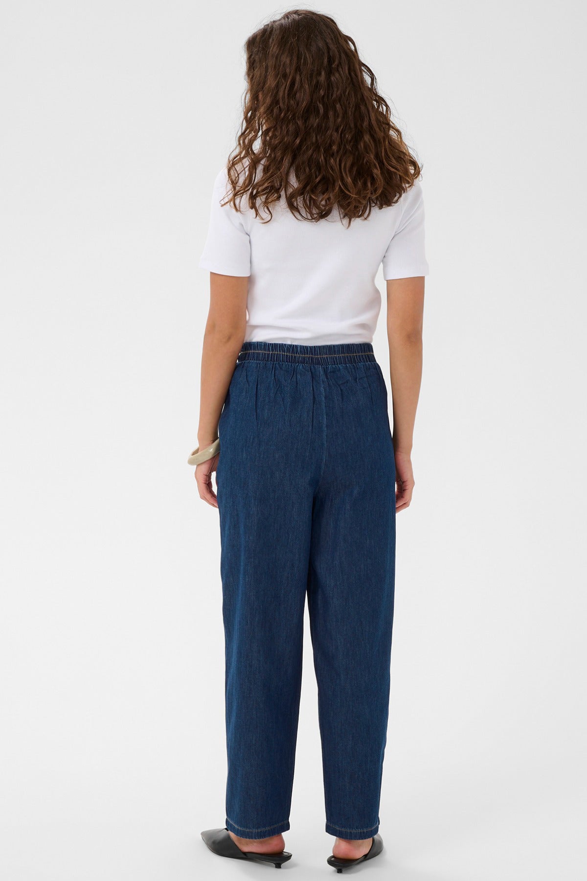 Mørkeblå denim bukser med elastisk talje og løs pasform set bagfra.