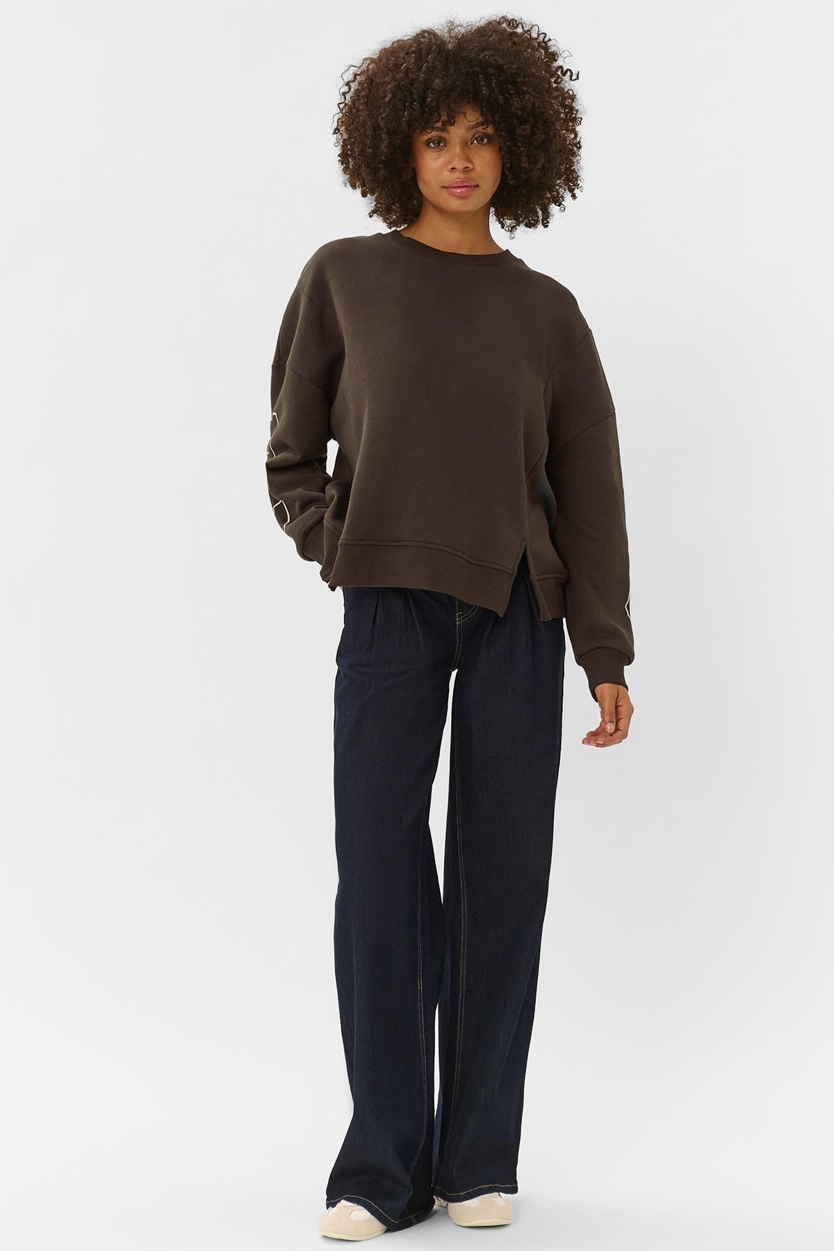Mørkebrun sweatshirt med rund hals og ribkanter, afslappet pasform og sideslidser foran.