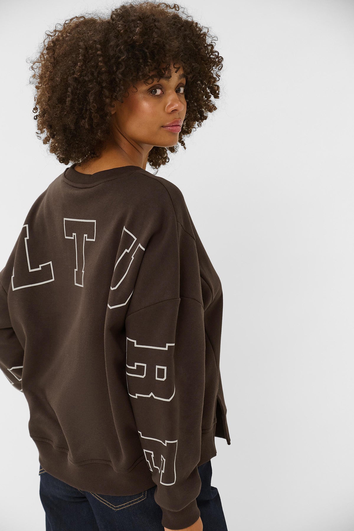 Brun sweatshirt med stort hvidt print på ryggen og afslappet pasform.