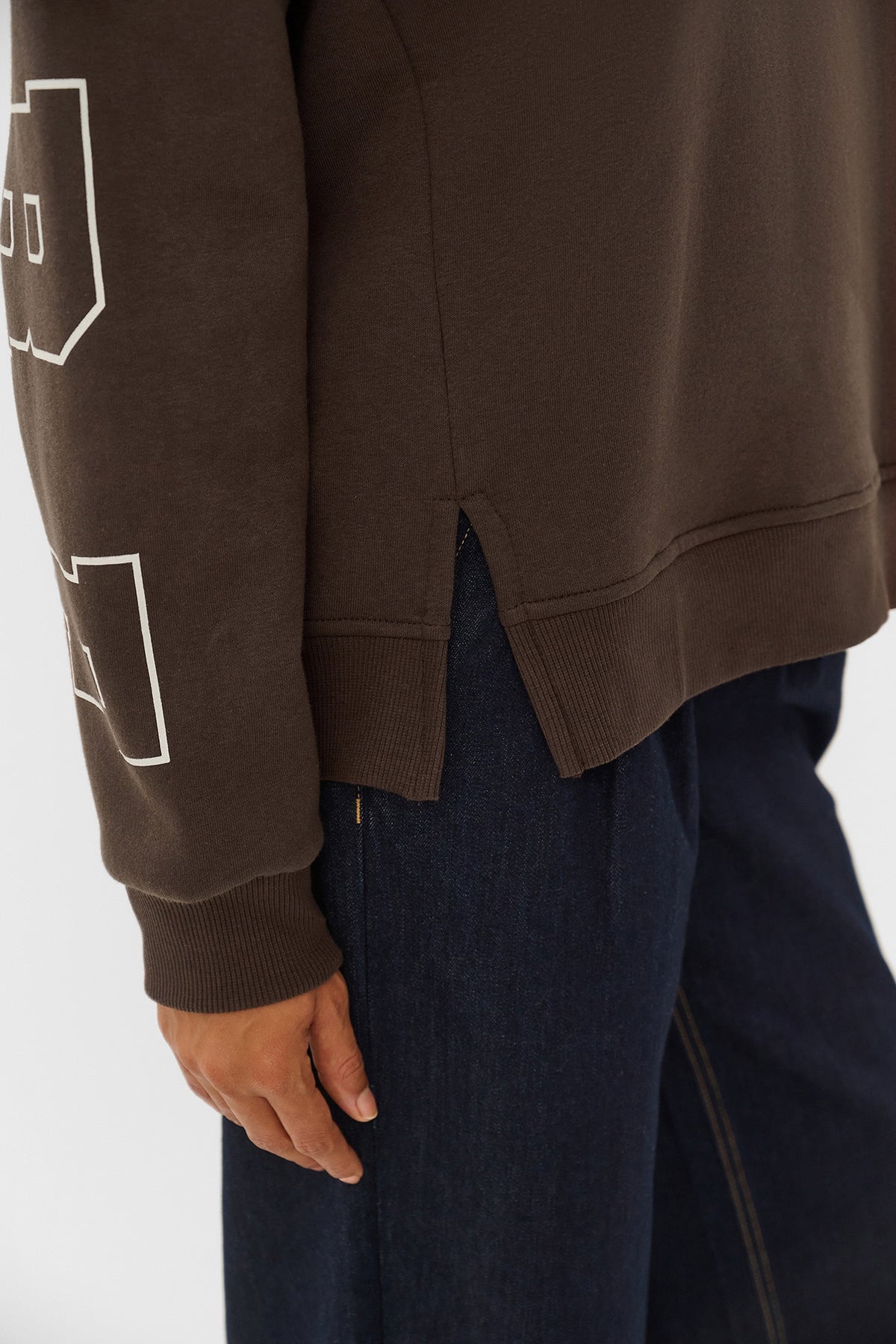 Brun sweatshirt med hvidt grafisk print på ærme og sidelommer, slidser i siden.