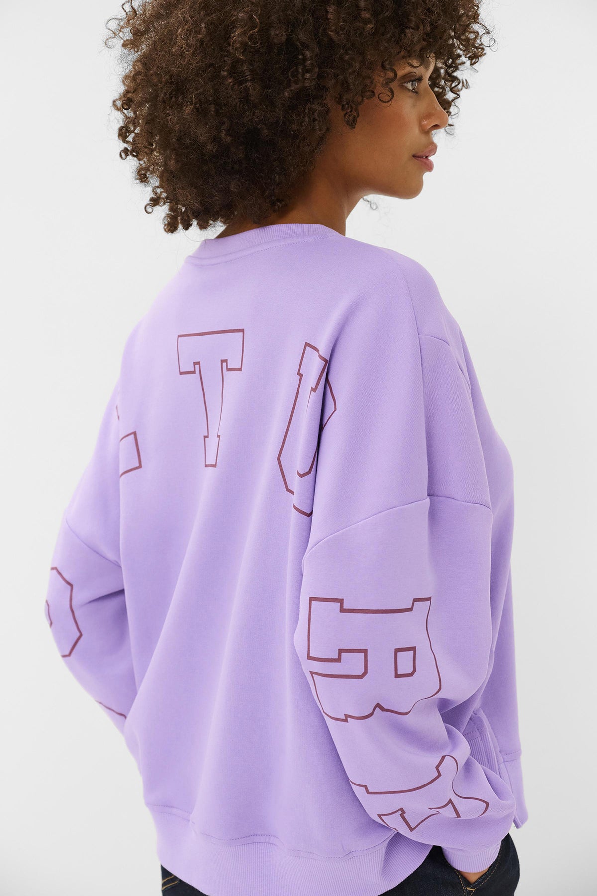 Lilla sweatshirt med løstsiddende ærmer og stort kontureret print på ryggen og ærmet.