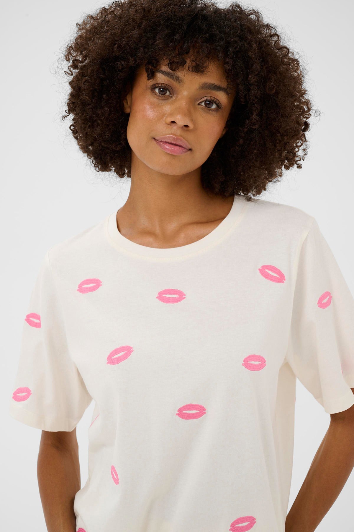 Hvid kortærmet t-shirt med lyserøde læbestiftsmærker og rund hals.