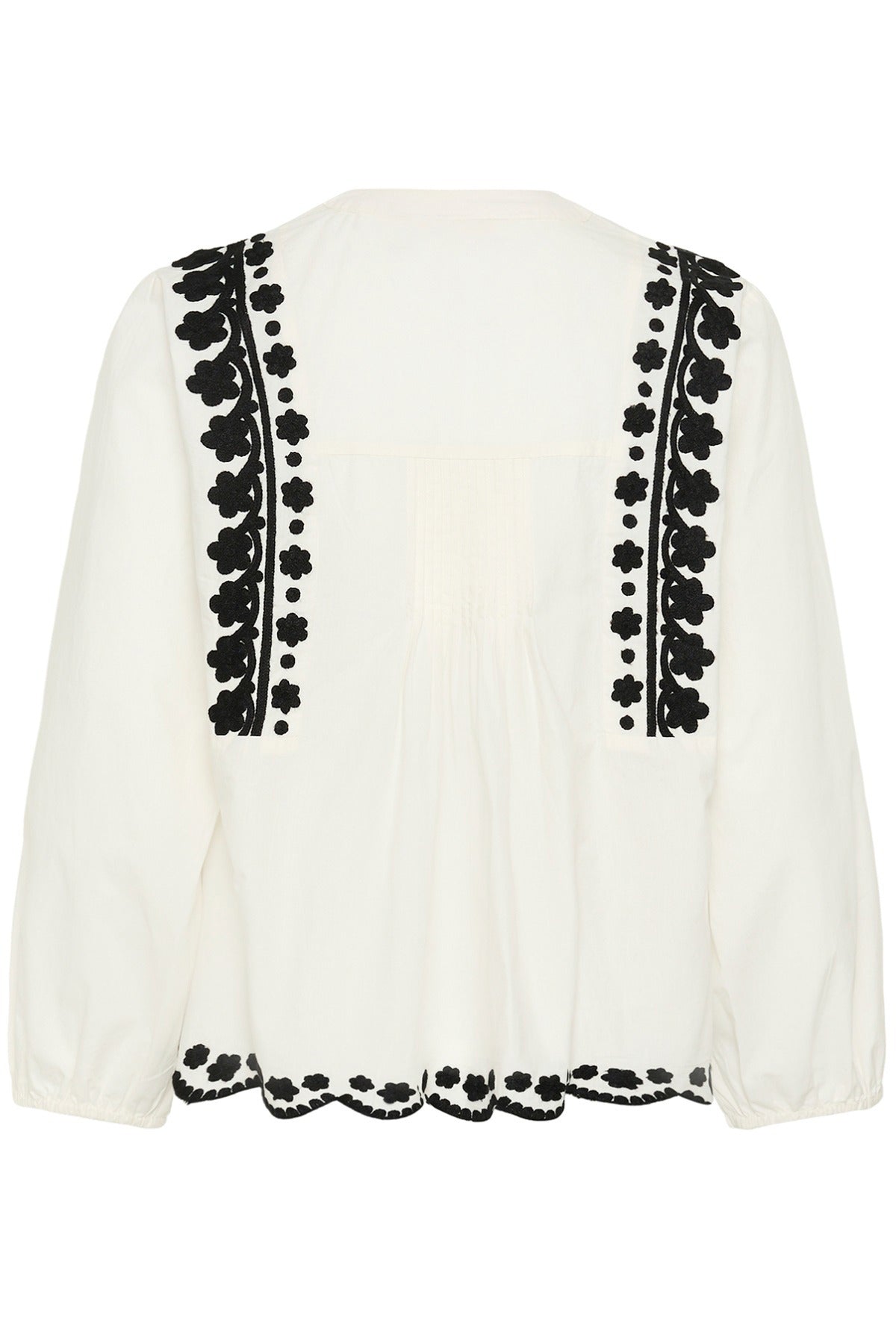Hvid bluse med lange ærmer og sort blomsterbroderi langs front og bund.