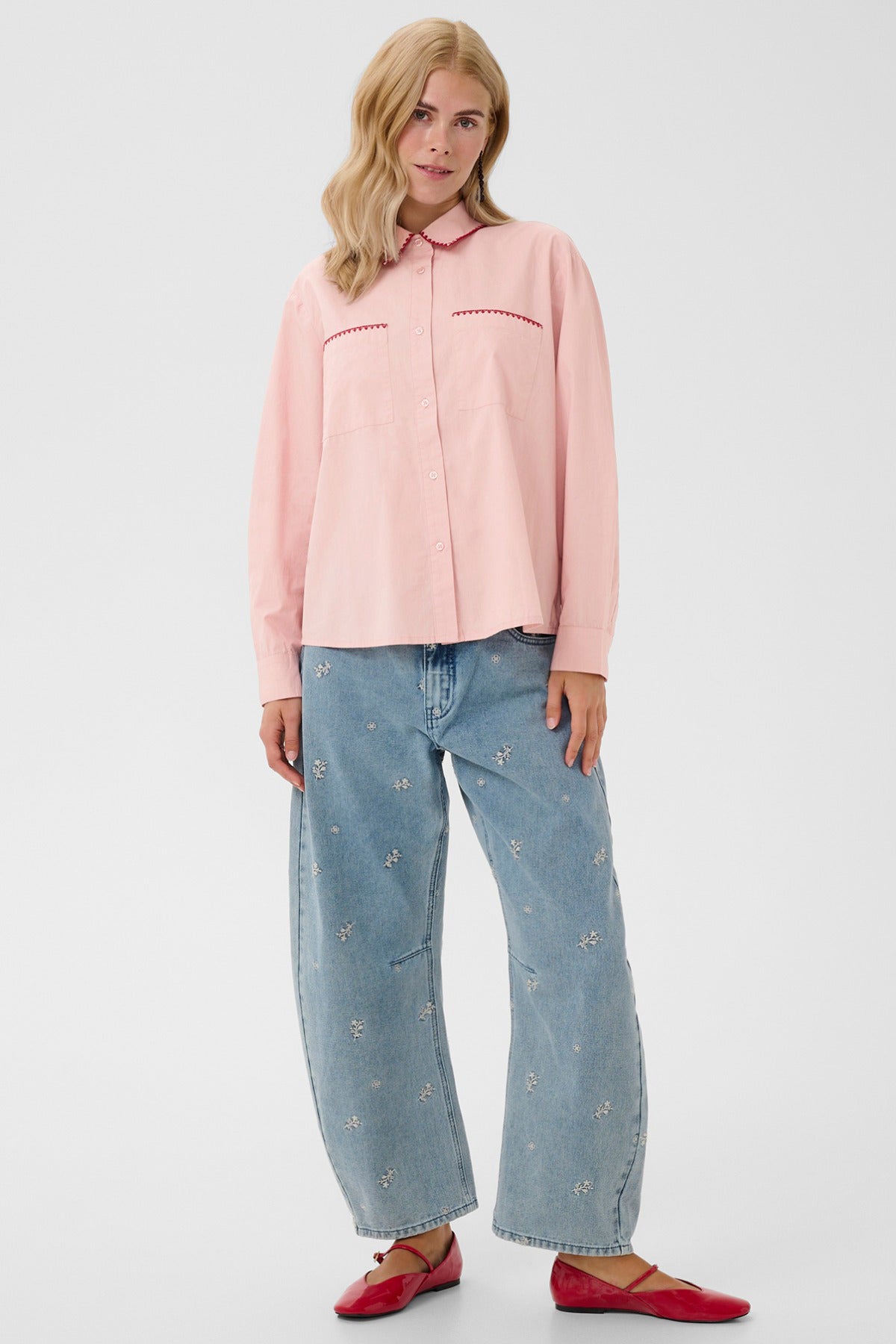 Lys rosa skjorte med lange ærmer og brystlommer, stylet med brede, lyseblå jeans.