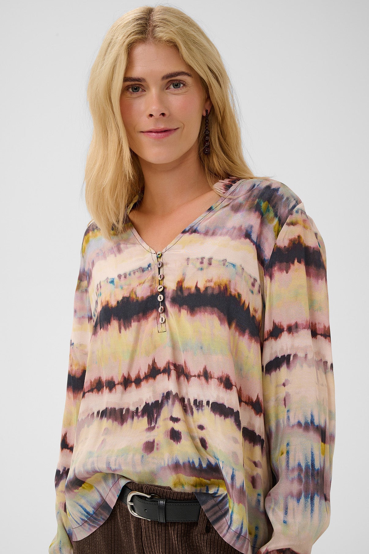 Bluse med langærmet design og abstrakt bølget mønster i nuancer af bordeaux, grøn og beige.