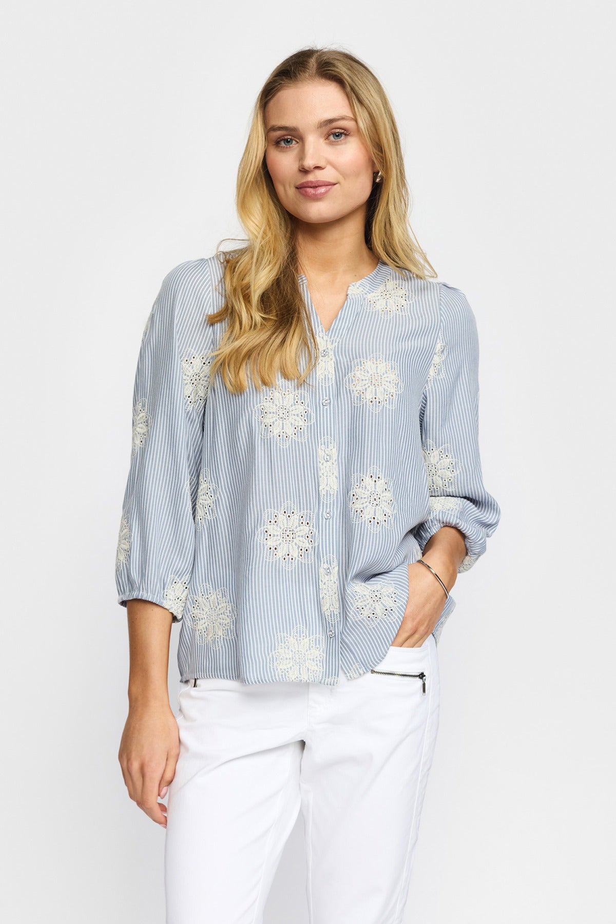 Lyseblå skjortebluse med hvide blomsterprint og trekvartærmer i afslappet pasform.