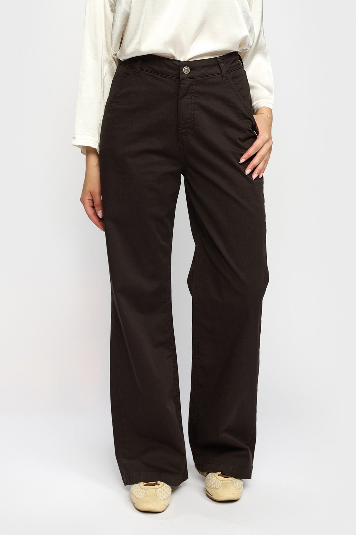 Brune stretchbukser med vide ben og høj talje, stylet med cremefarvet bluse og beige sko.