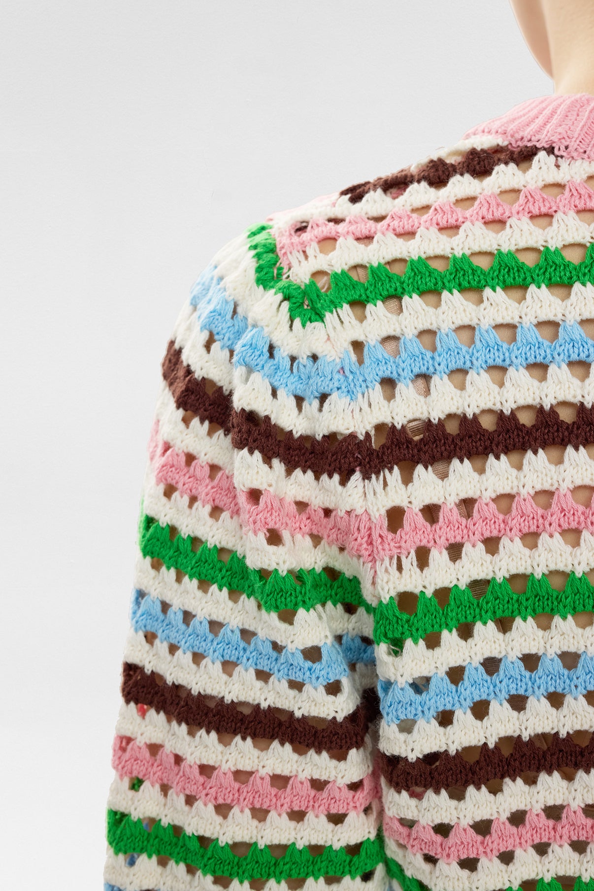 Strikket pullover i pink, brun, grøn, blå og hvide striber med hulmønster.