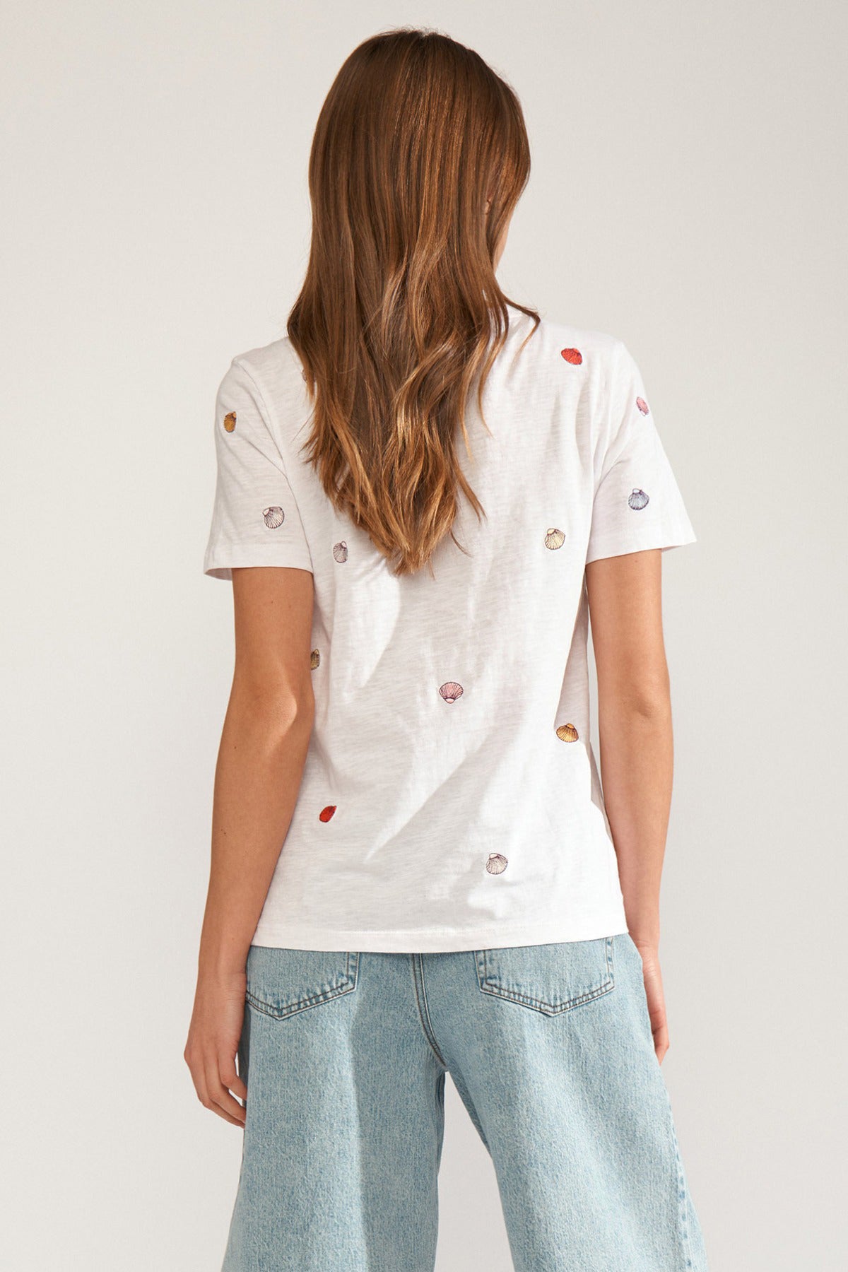 Hvid T-shirt med små broderede muslingedetaljer på ryggen, kortærmet, afslappet pasform.