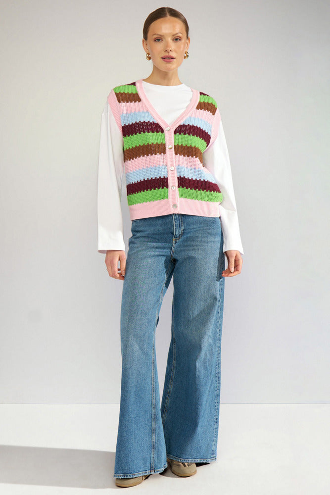 Stribet hæklet strikvest i rosa, brun, grøn og hvid, knaplukning foran, model med hvide ærmer og blå vidde jeans.