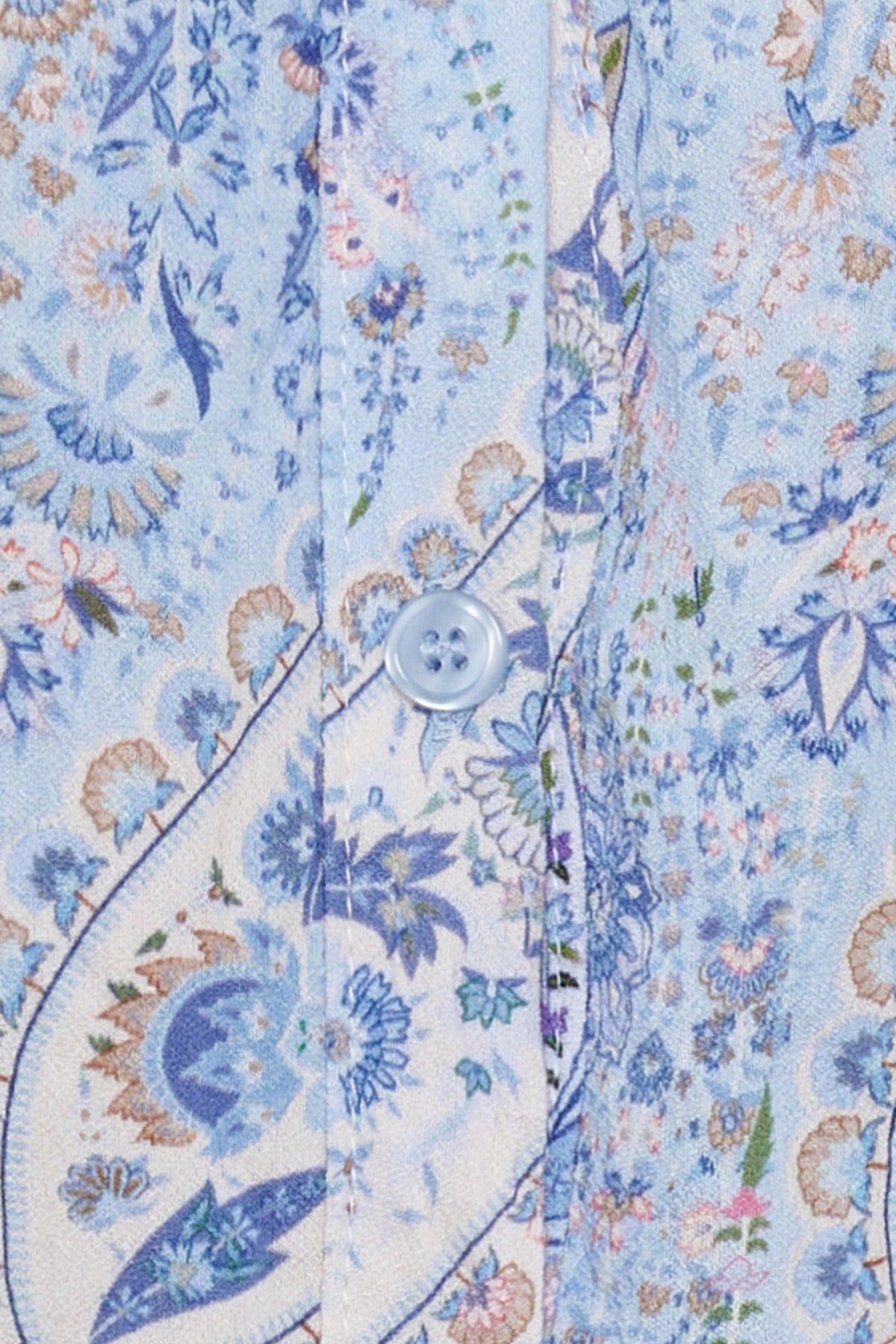 Lyseblå skjortebluse med små blomstermønstre i blå, beige og rosa og klare knapper.
